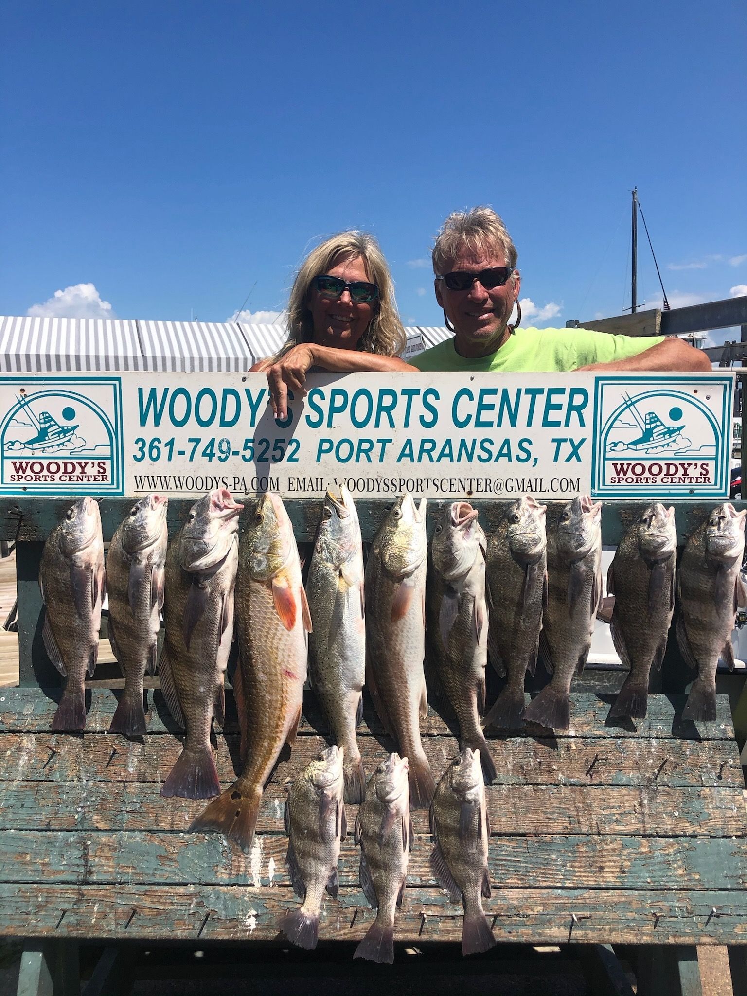 A man and a woman are posing for a picture with a bunch of fish.
