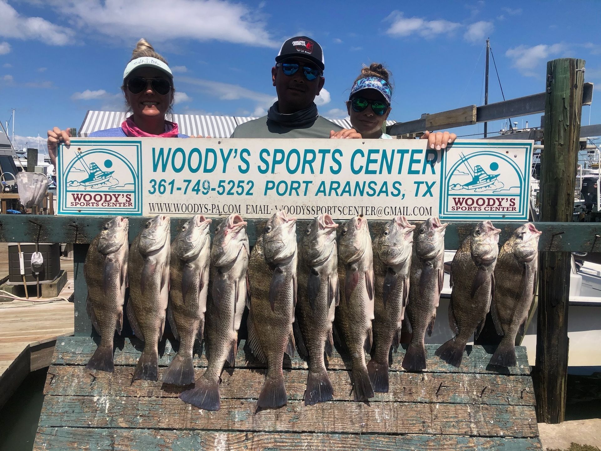 A group of people standing next to each other holding a bunch of fish.