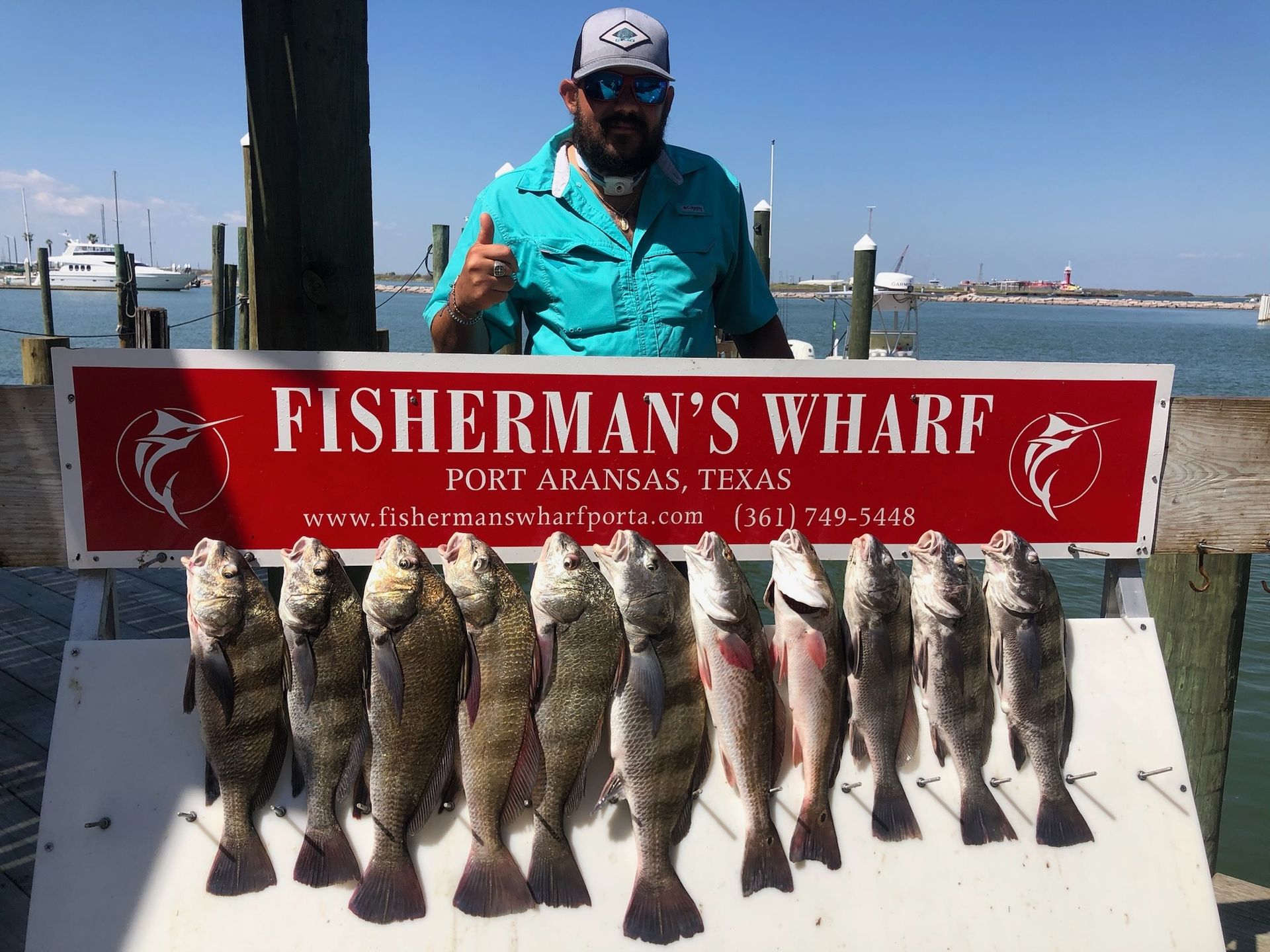 A man is standing next to a sign that says fisherman 's wharf