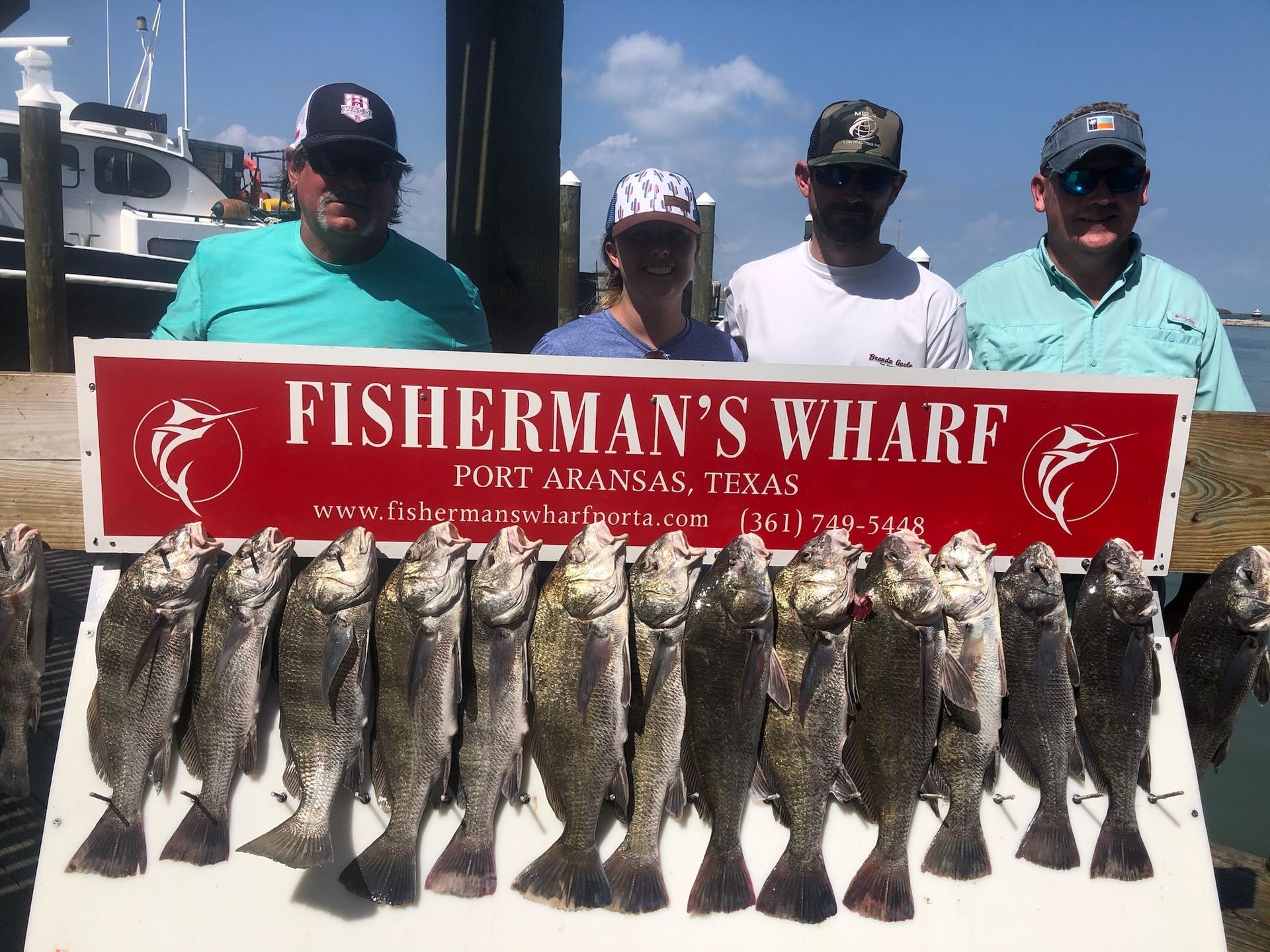 A group of men are standing next to a sign that says fisherman 's wharf.