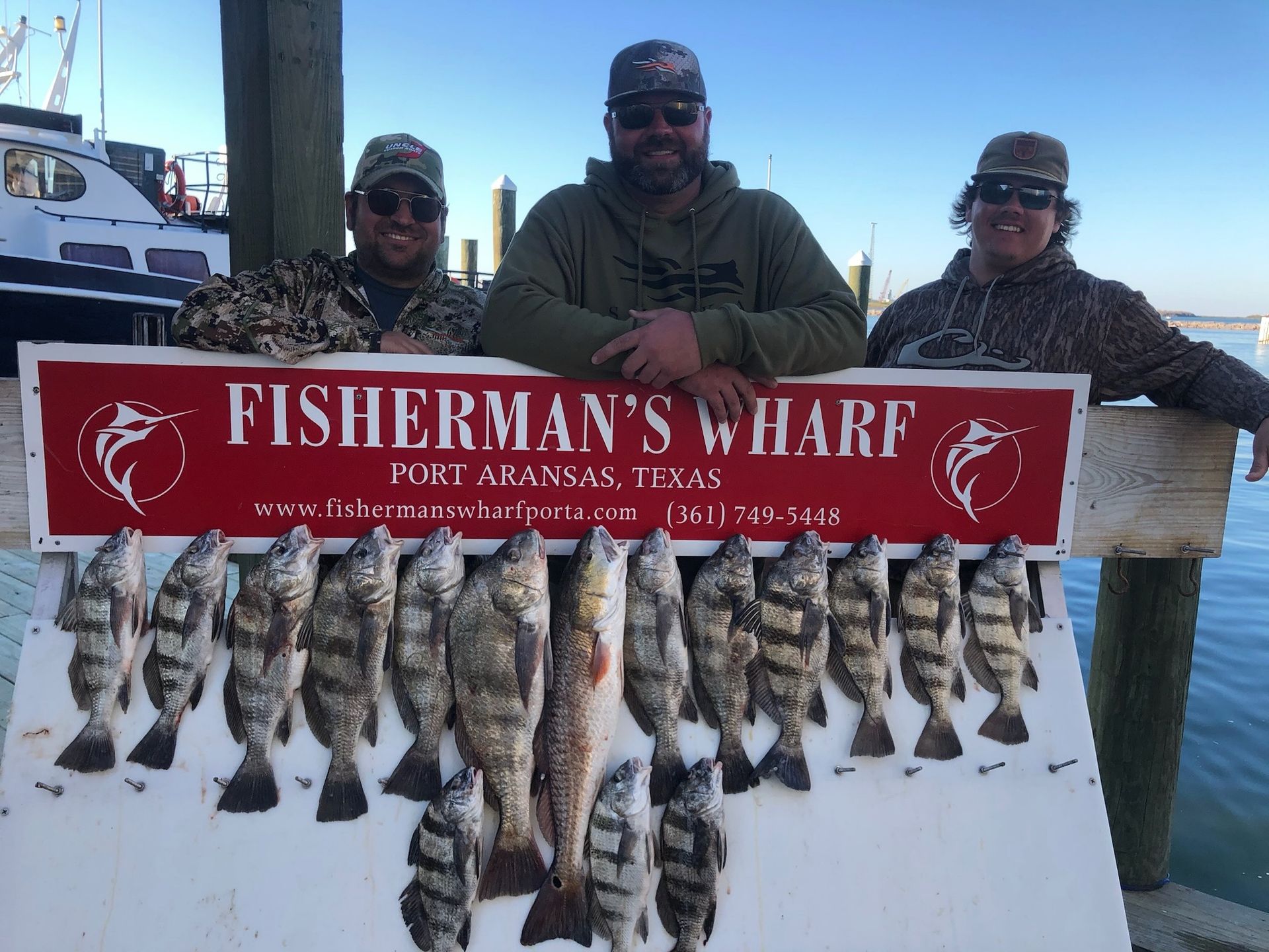 Three men are standing next to a sign that says fisherman 's wharf