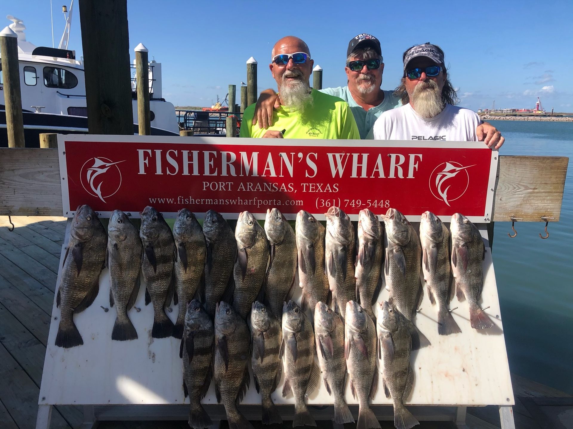Three men are posing for a picture with a sign that says fisherman 's wharf