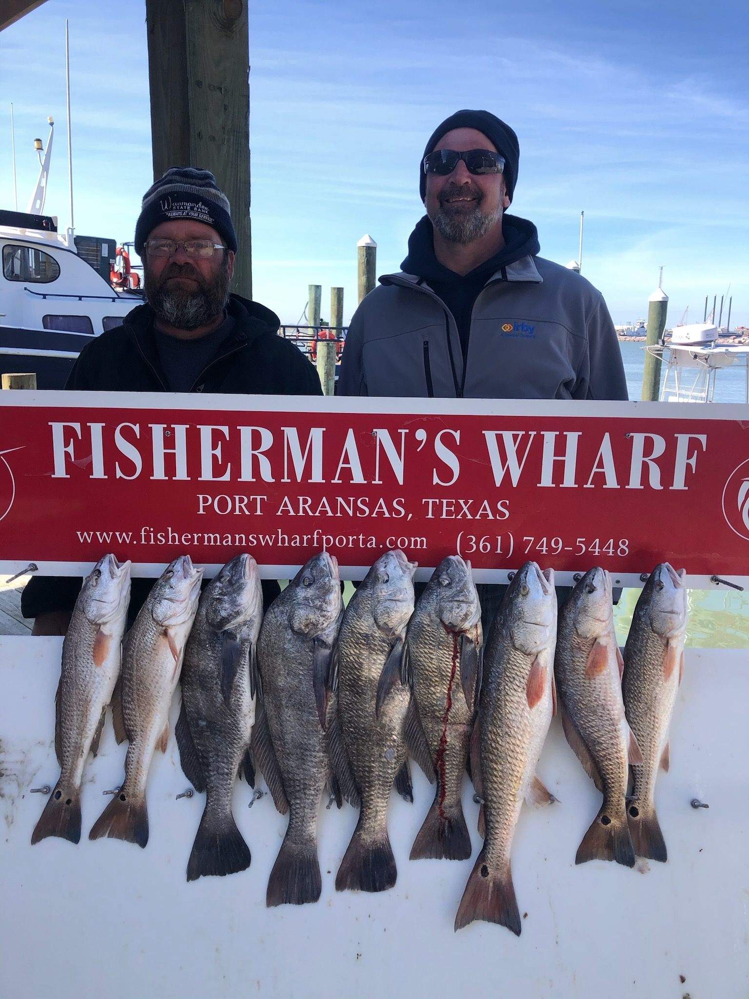 Two men holding a sign that says fisherman 's wharf