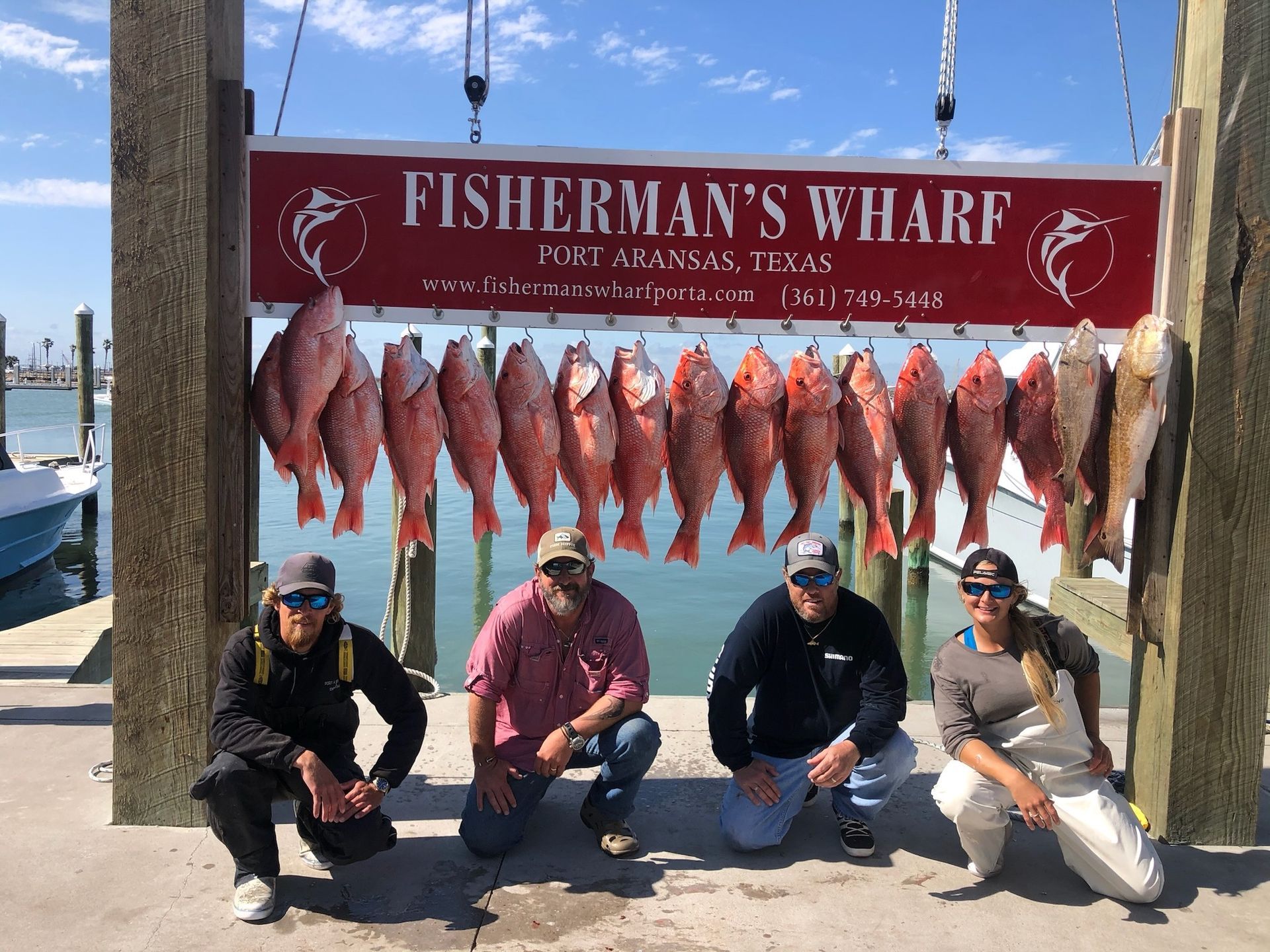 A group of people standing in front of a sign that says fisherman 's wharf