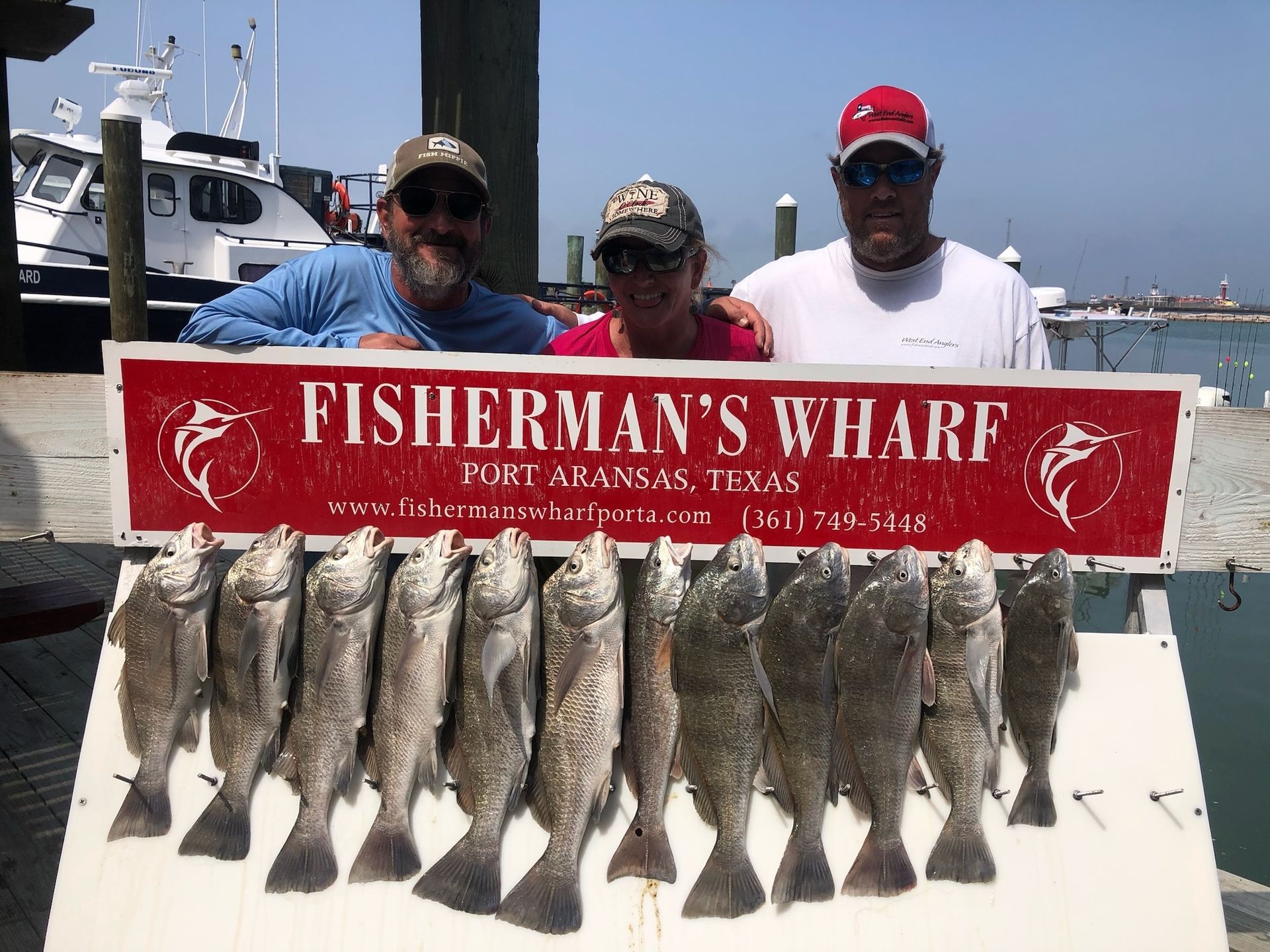 Three men are holding a sign that says fisherman 's wharf