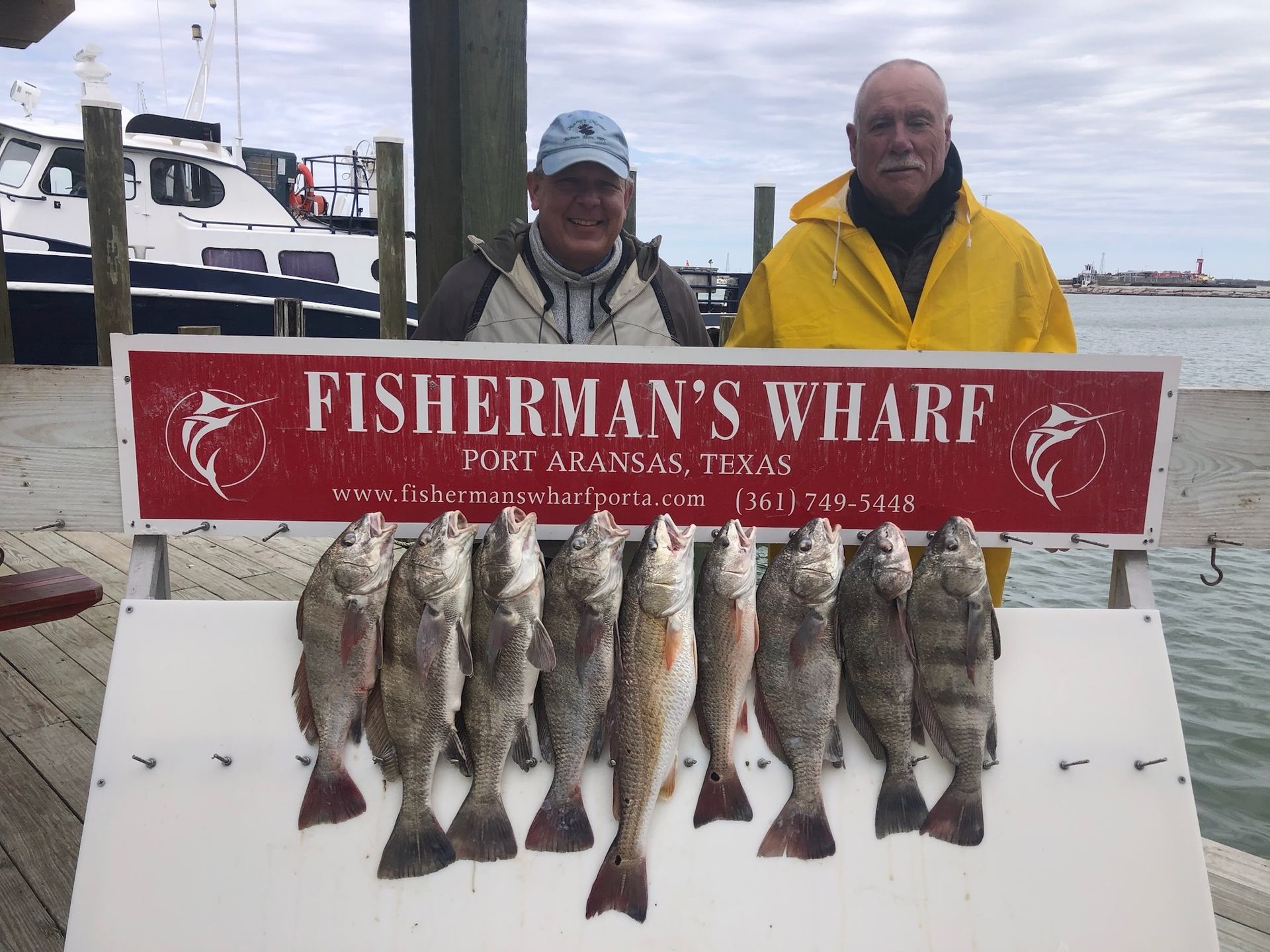 Two men standing next to a sign that says fisherman 's wharf