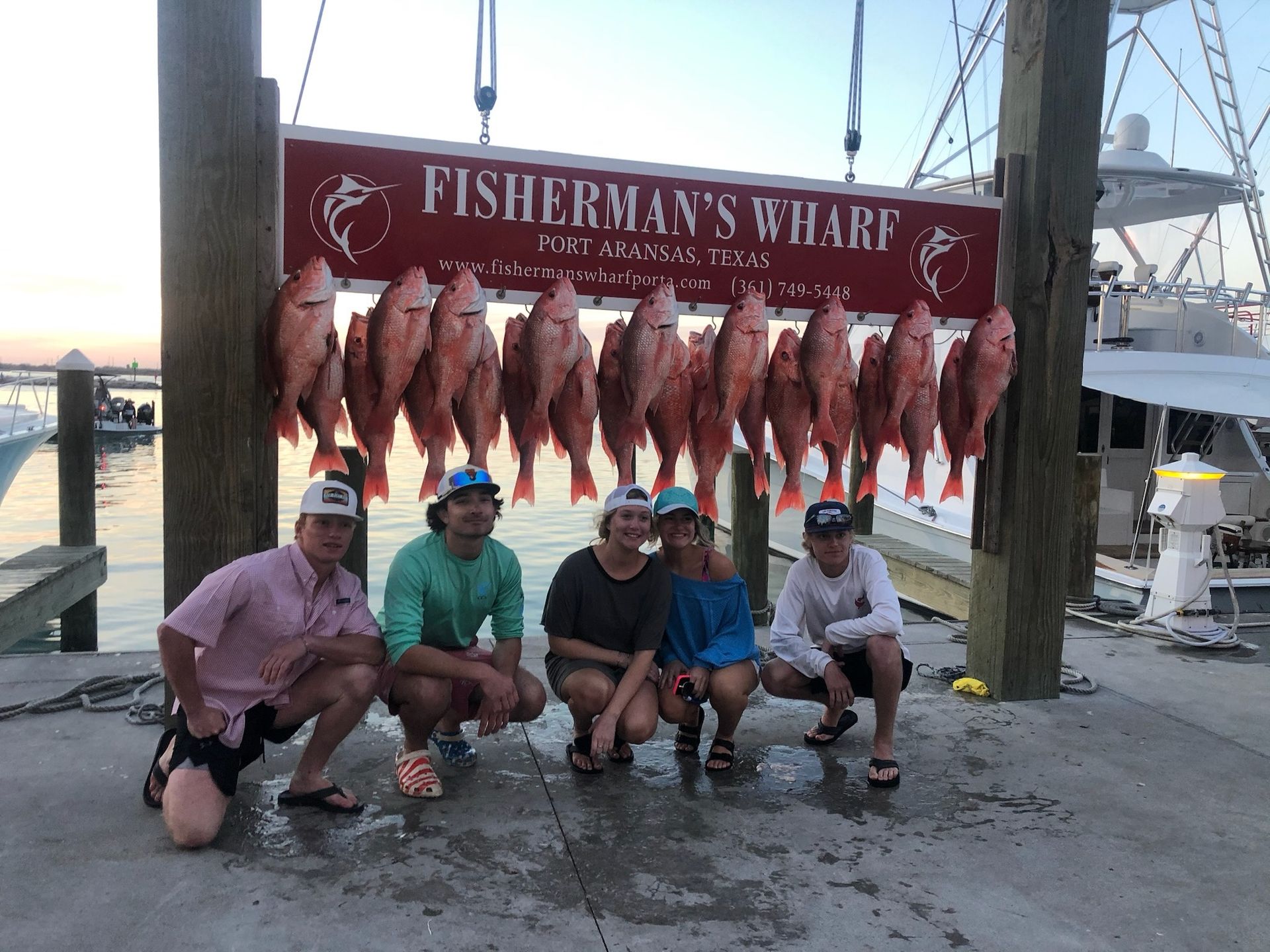A group of people are posing for a picture in front of a sign that says fisherman 's wharf