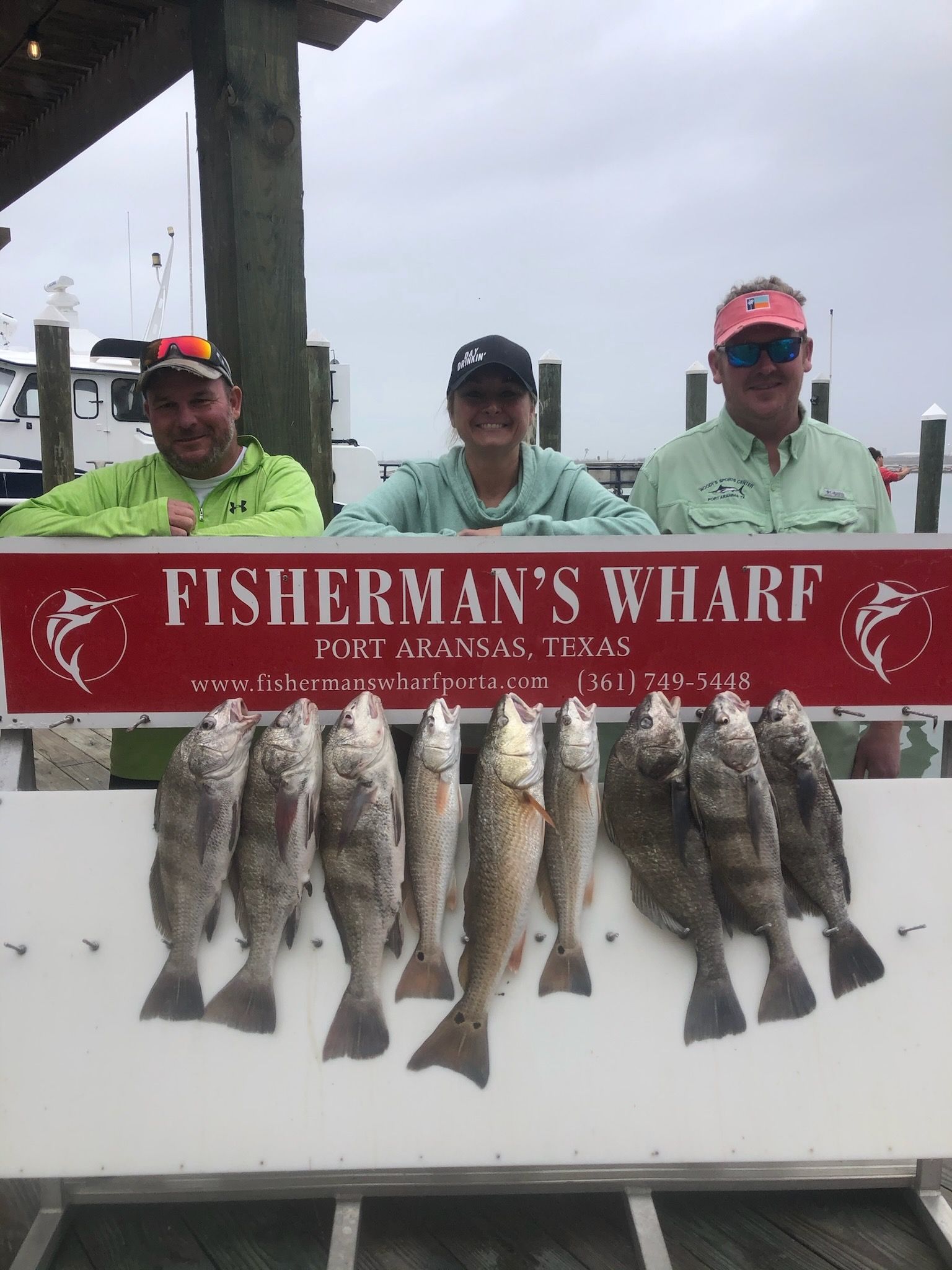A group of men are standing next to a sign that says fisherman 's wharf.