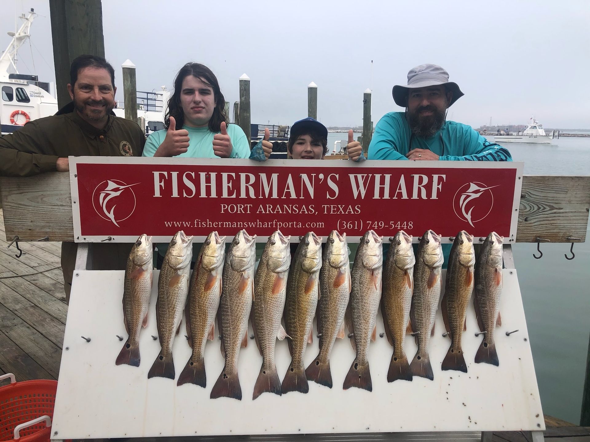 A group of people standing next to a sign that says fisherman 's wharf