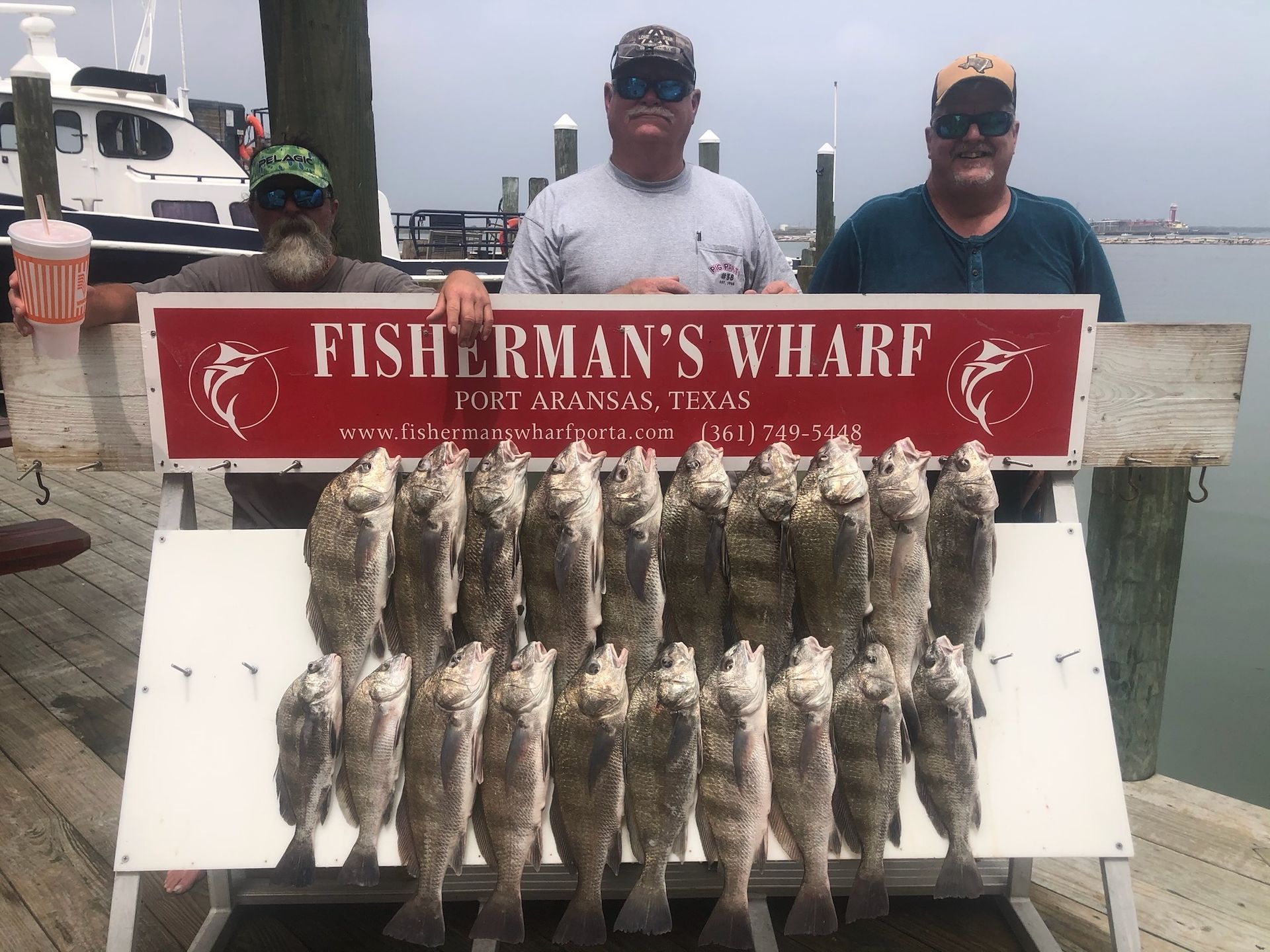 Three men holding a sign that says fisherman 's wharf