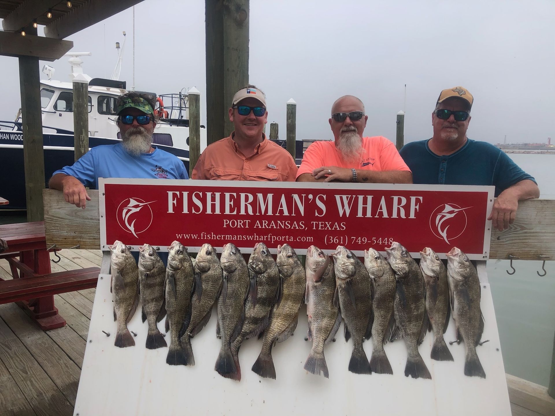 A group of men standing next to a sign that says fisherman 's wharf