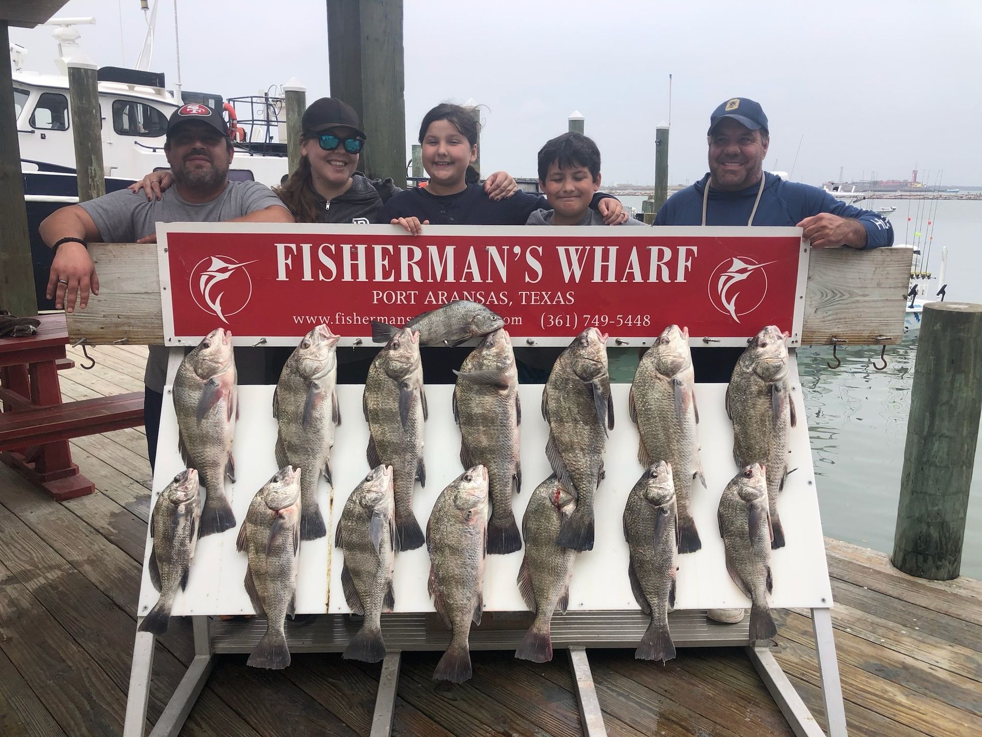 A group of people are posing for a picture with a sign that says fisherman 's wharf.