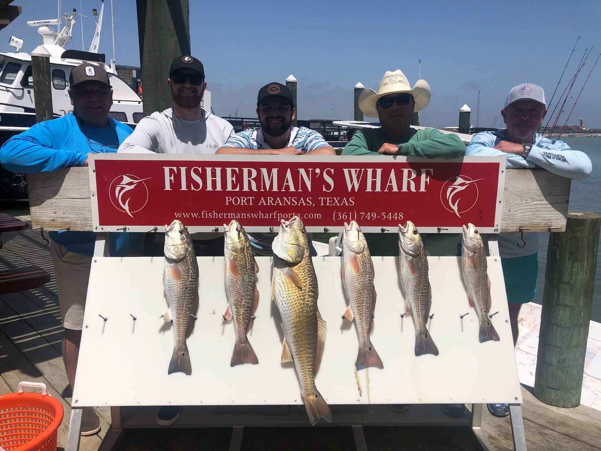 A group of men are standing next to a sign that says fisherman 's wharf.