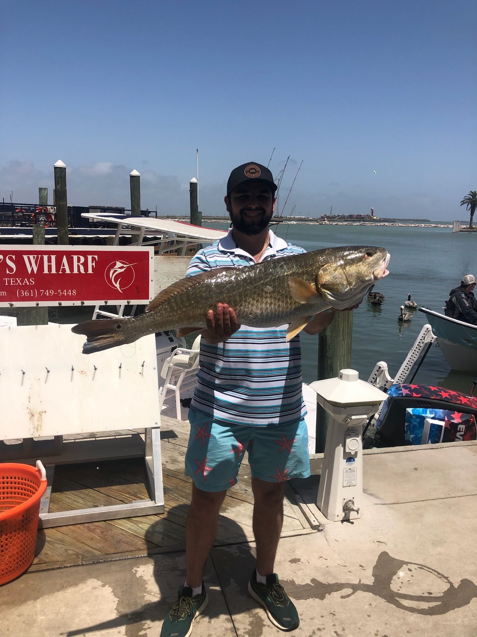 A man is holding a large fish in front of a body of water.