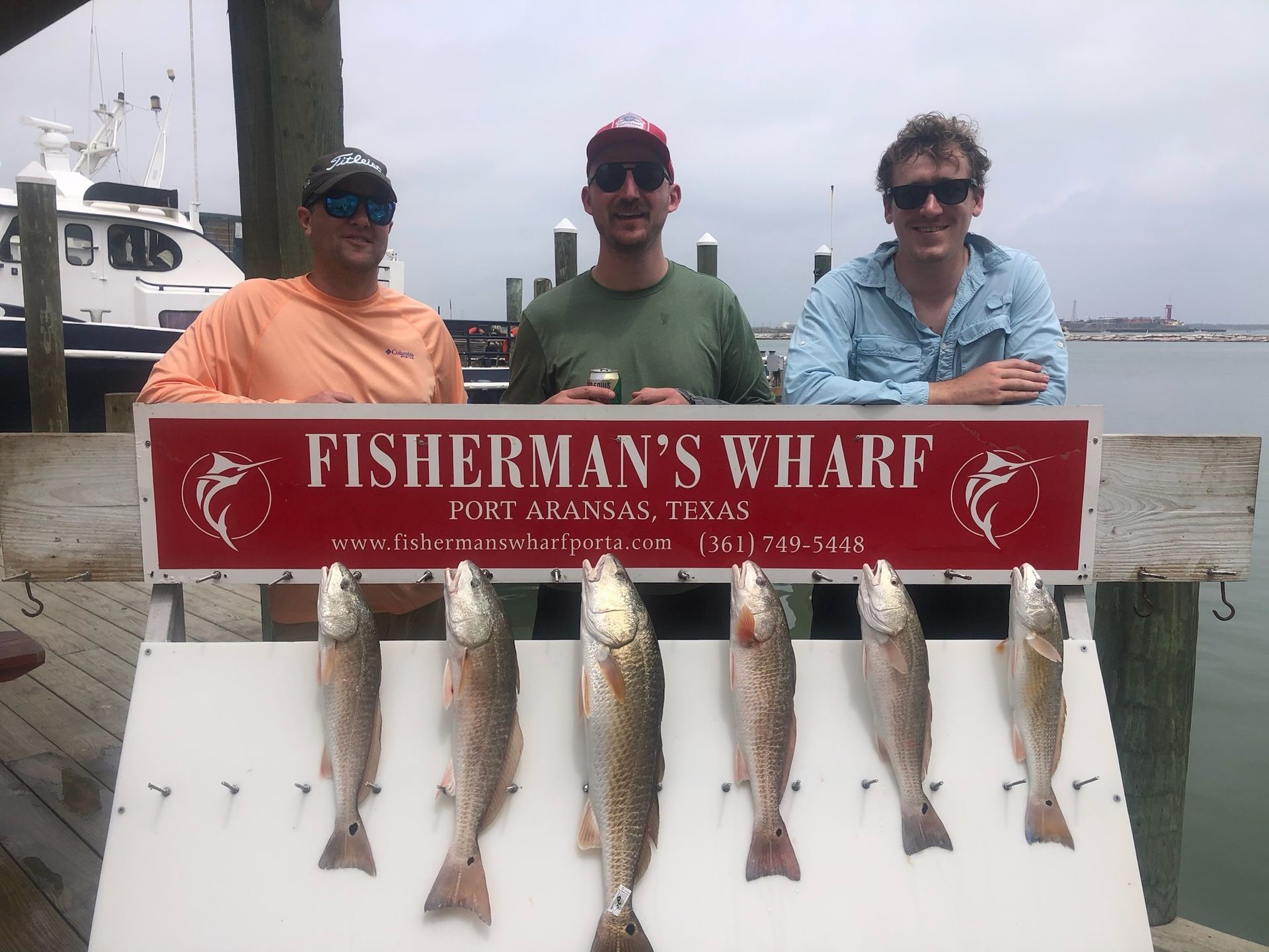 Three men standing next to a sign that says fisherman 's wharf