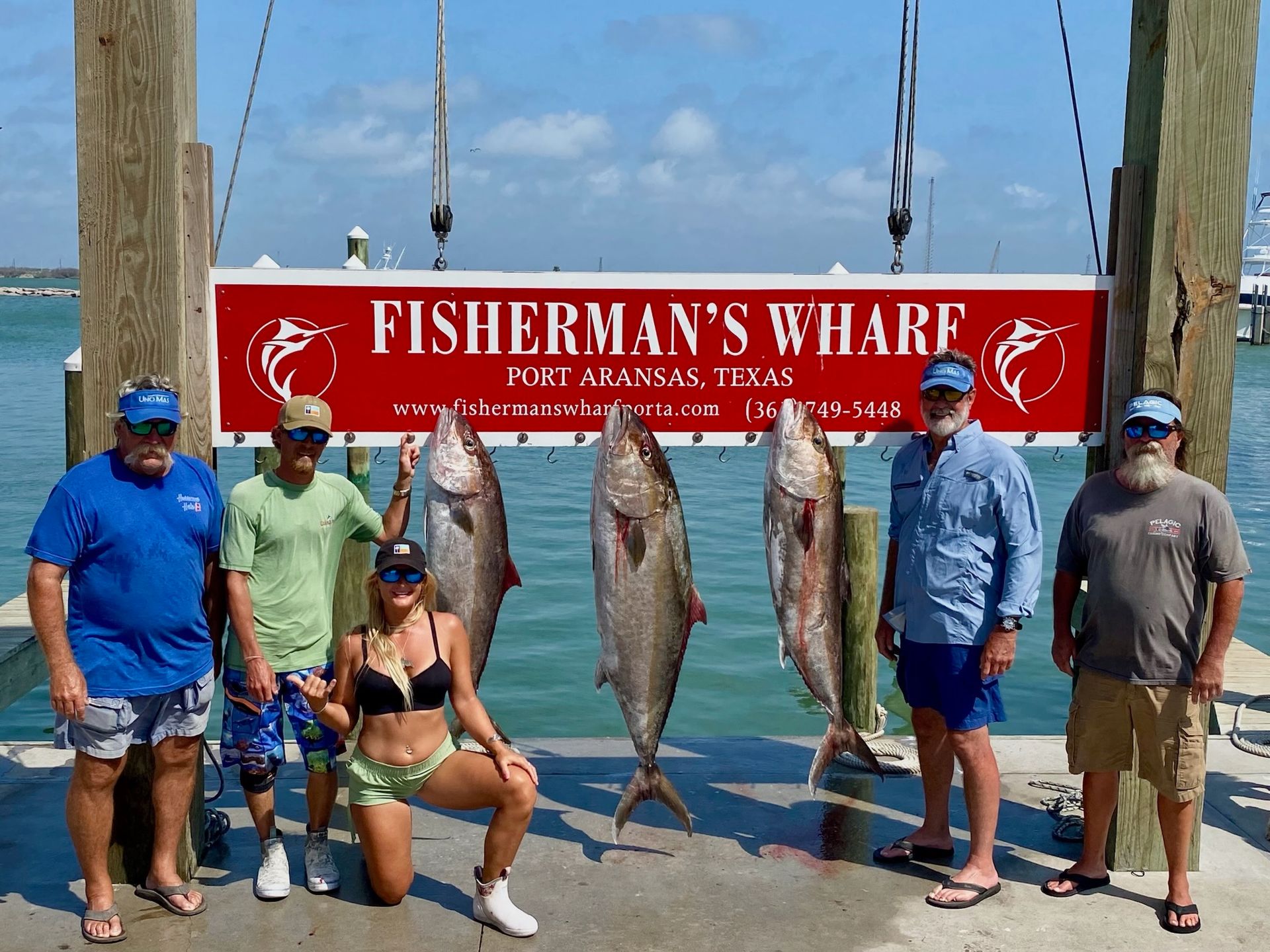 A group of people standing in front of a sign that says fisherman 's wharf