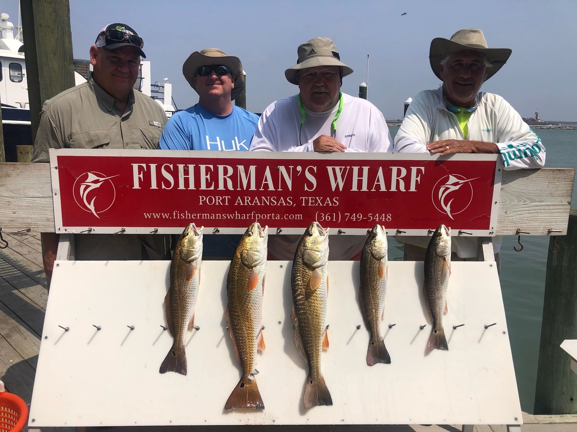 A group of men standing next to a sign that says fisherman 's wharf