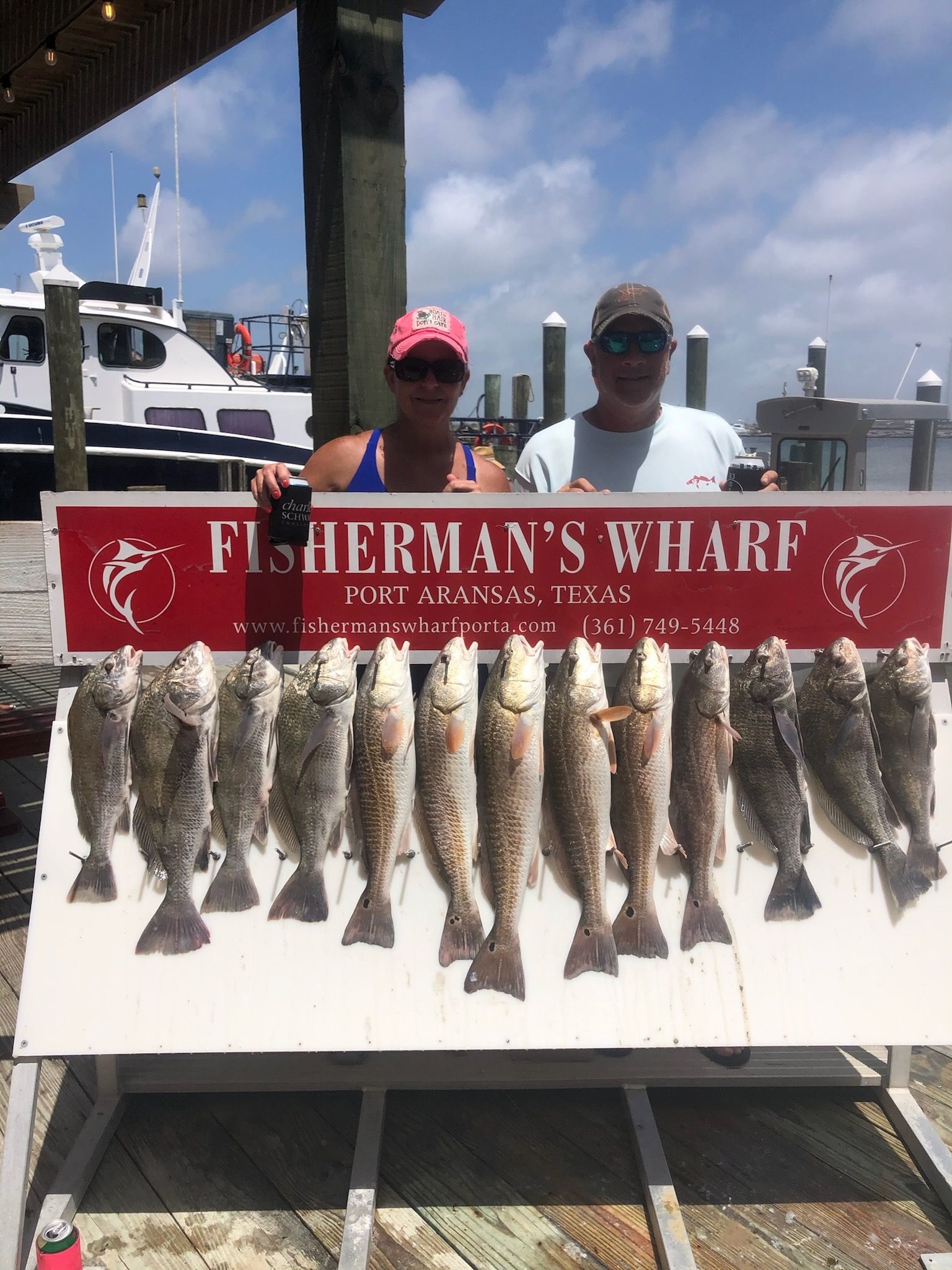A man and a woman are holding a sign that says fisherman 's wharf.