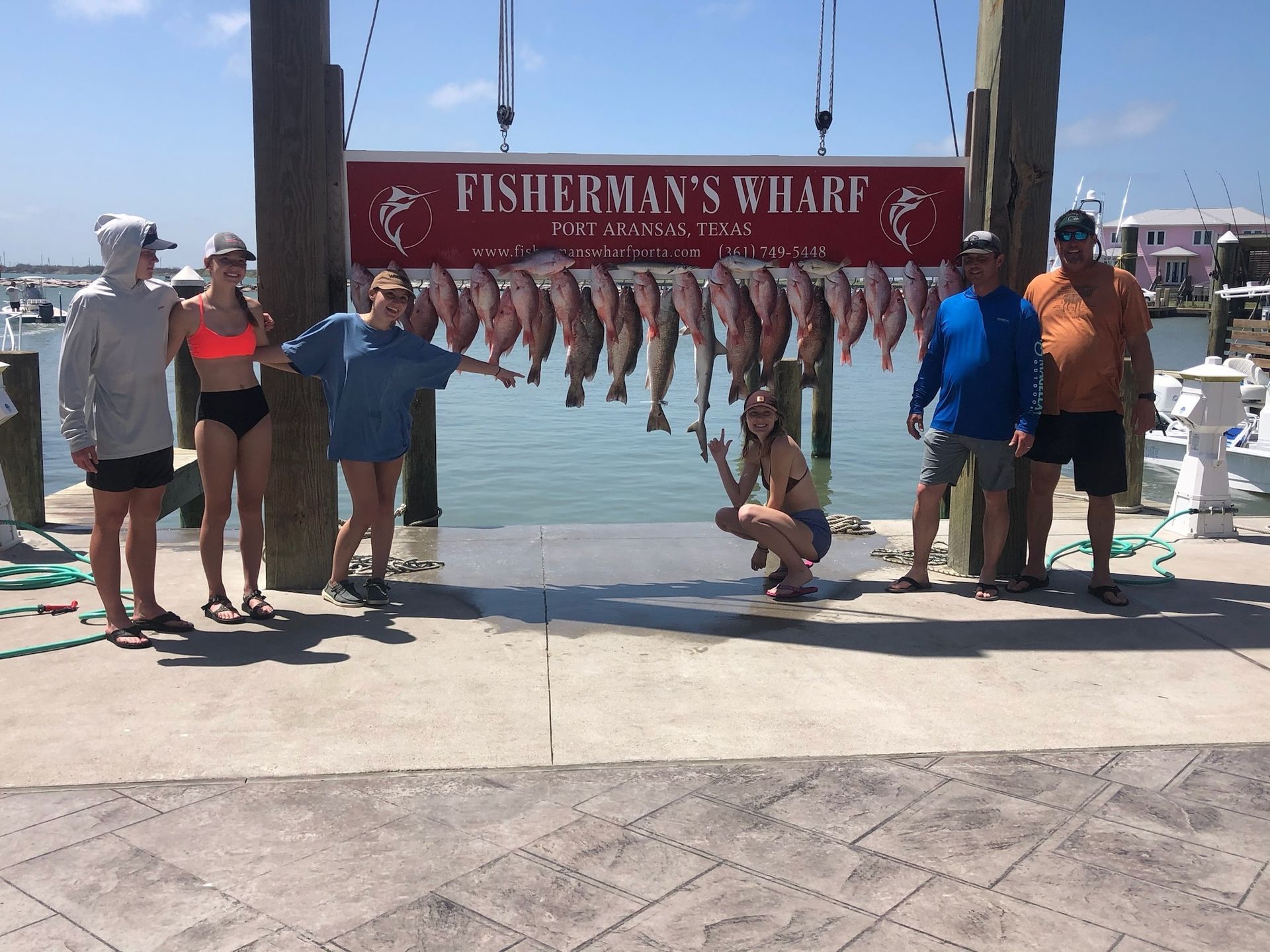 A group of people standing in front of a sign that says fisherman 's wharf