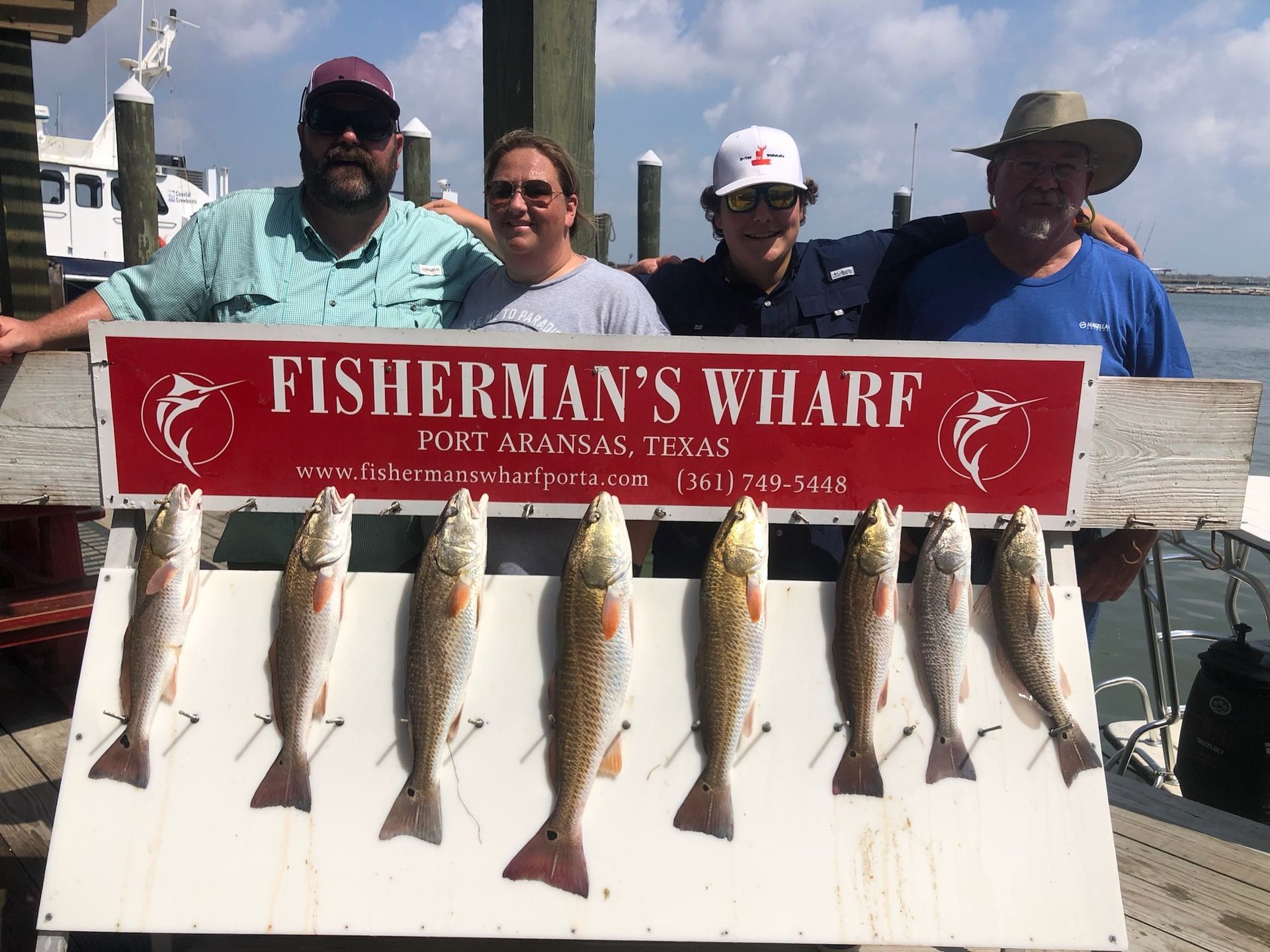 A group of people standing next to a sign that says fisherman 's wharf