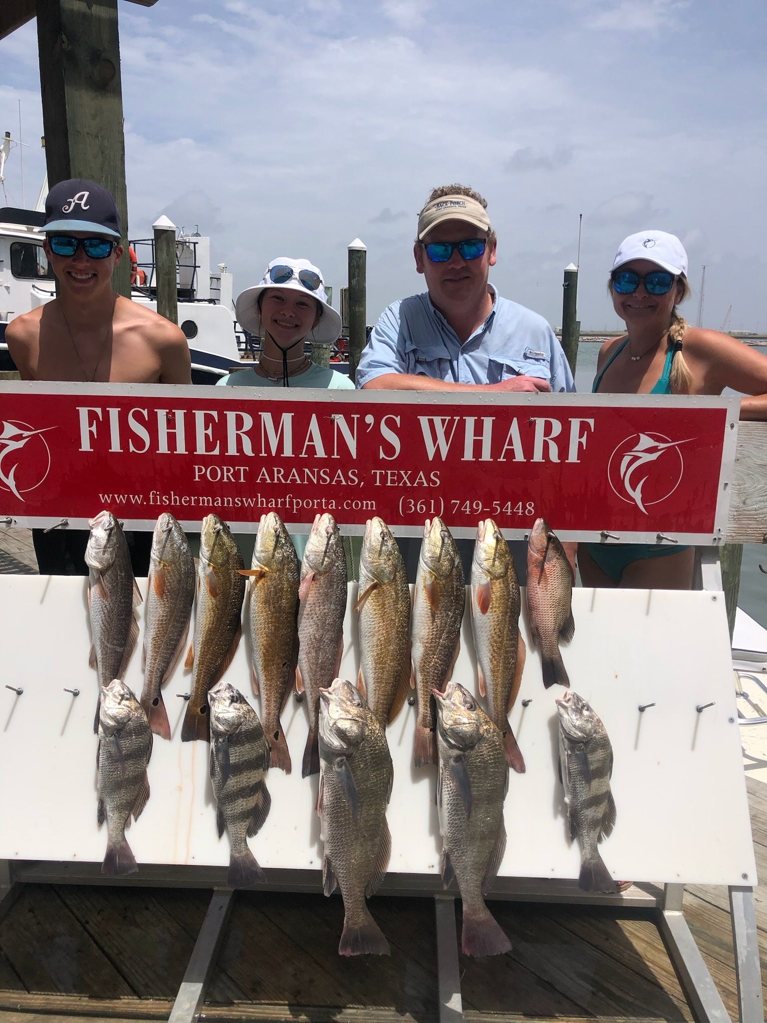 A group of people standing next to a sign that says fisherman 's wharf