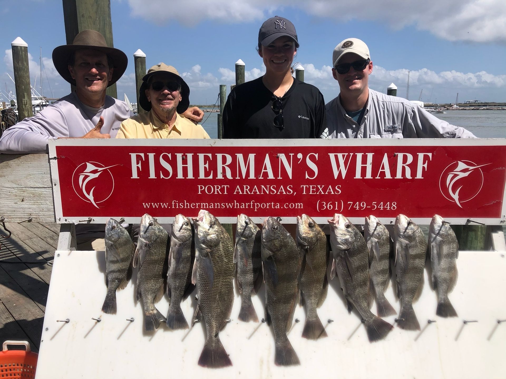 A group of people standing next to a sign that says fisherman 's wharf