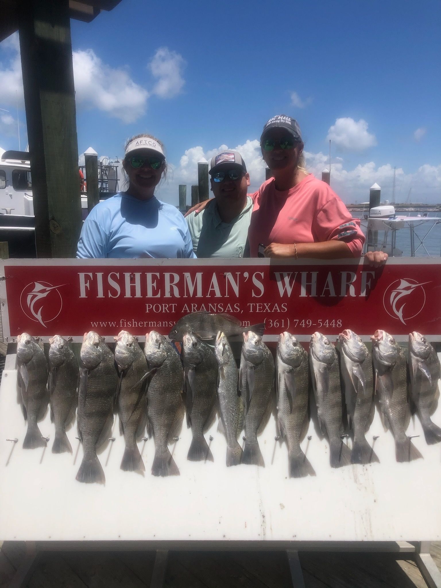 A group of people standing in front of a sign that says fisherman 's wharf.