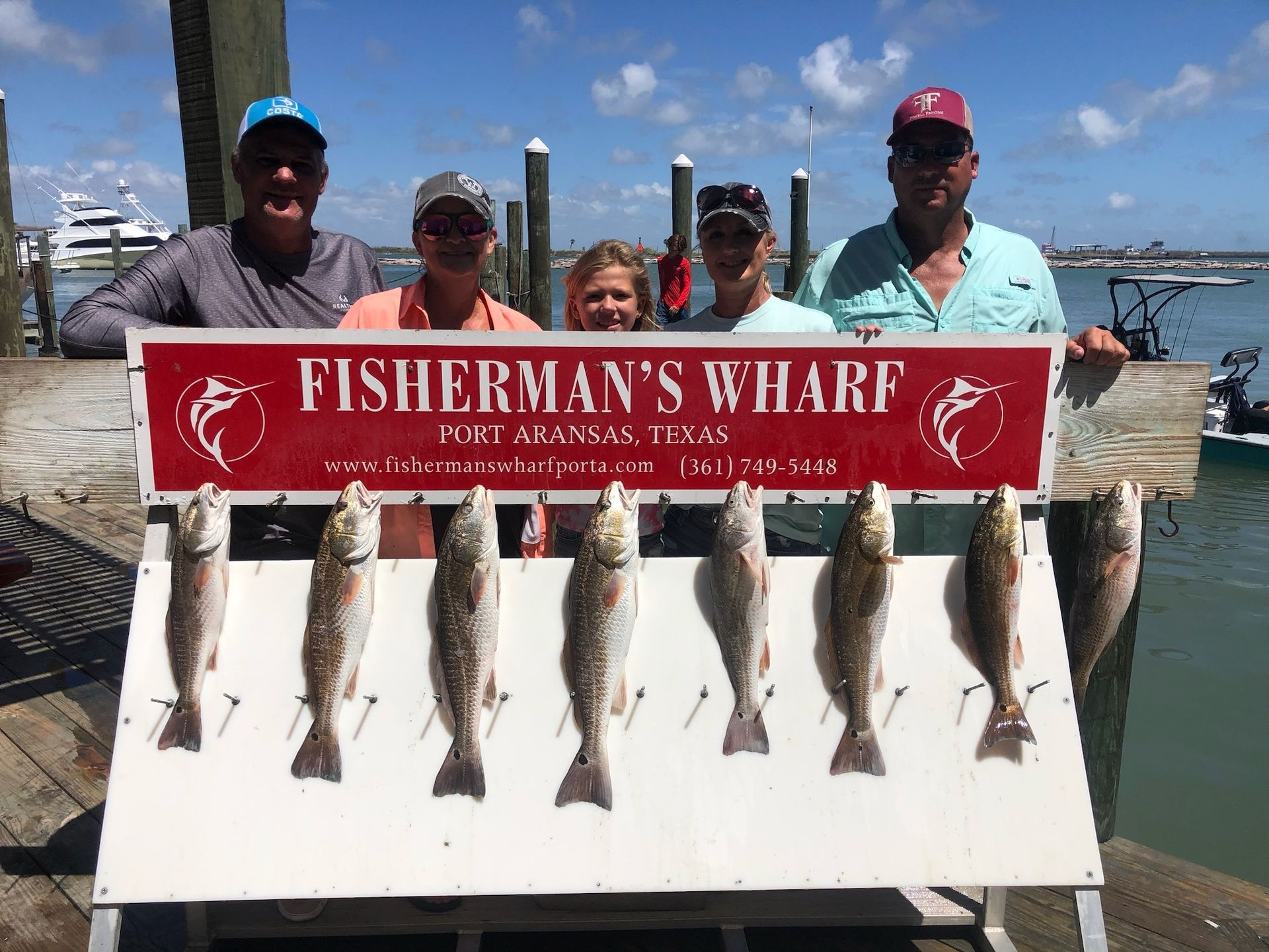 A group of people are standing next to a sign that says fisherman 's wharf.