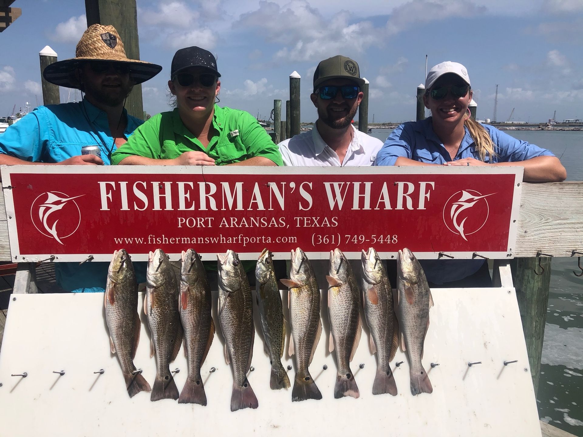 A group of people standing next to a sign that says fisherman 's wharf