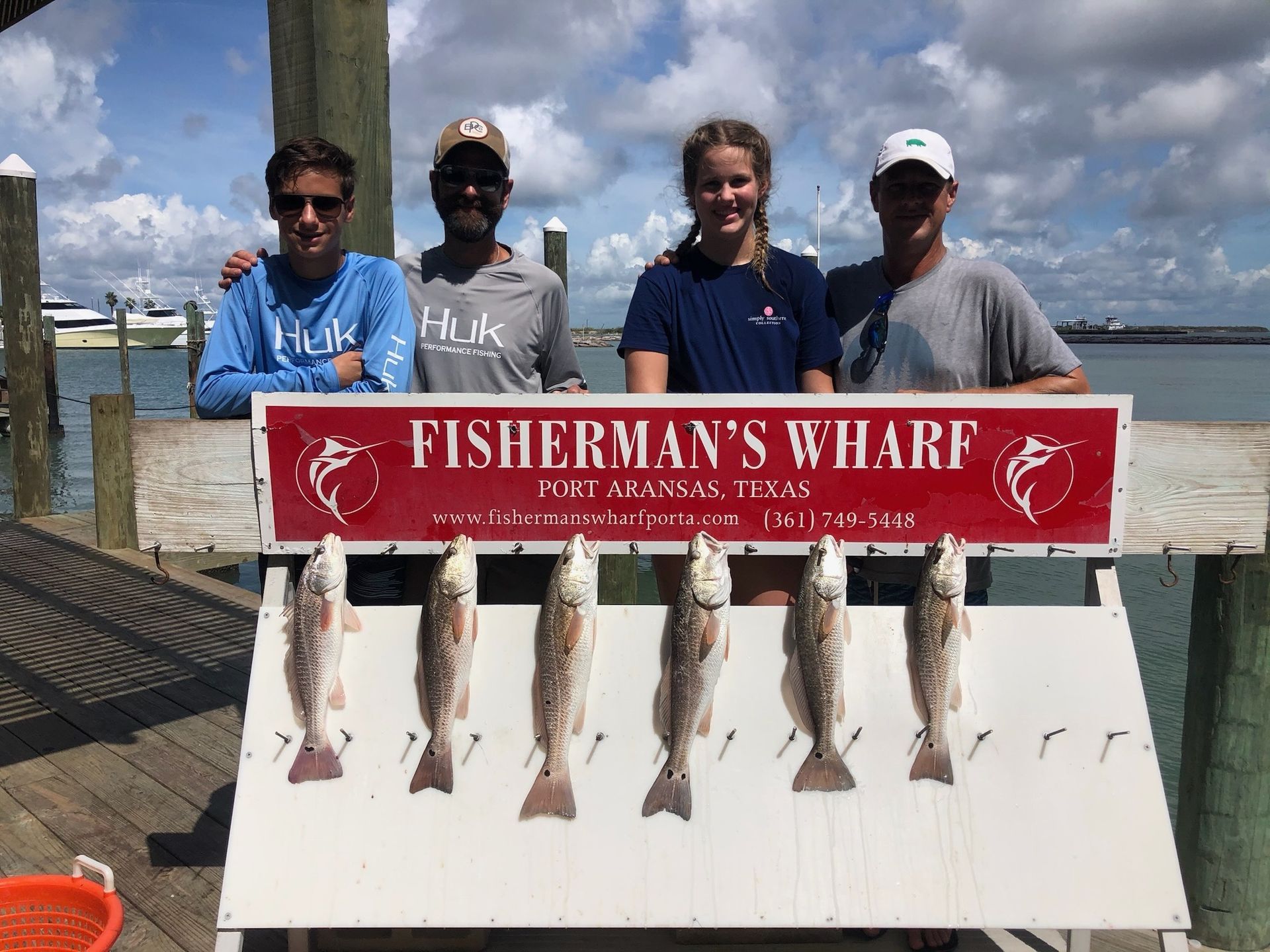 A group of people standing next to a sign that says fisherman 's wharf.