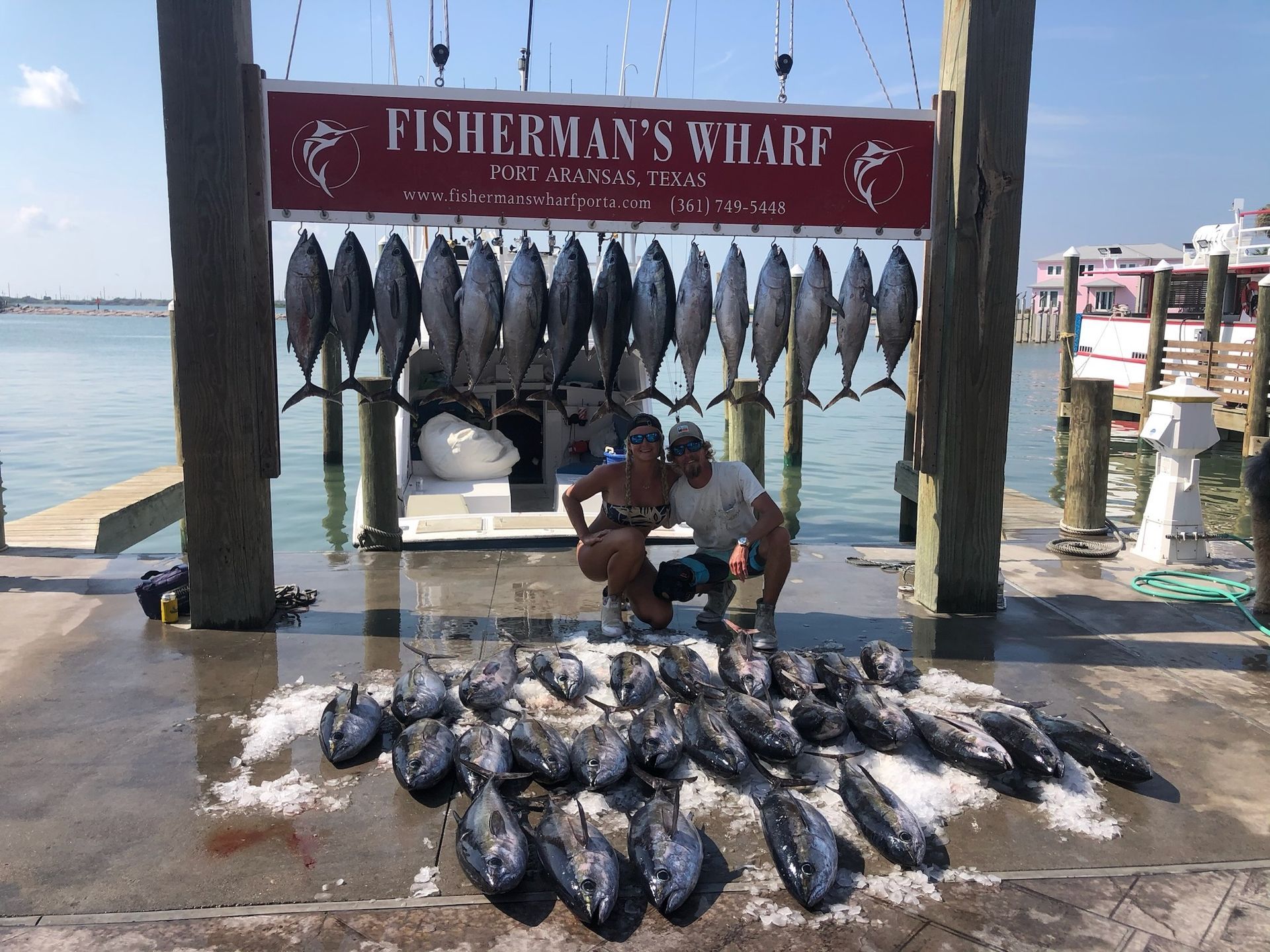 Two men are standing in front of a sign that says fisherman 's wharf