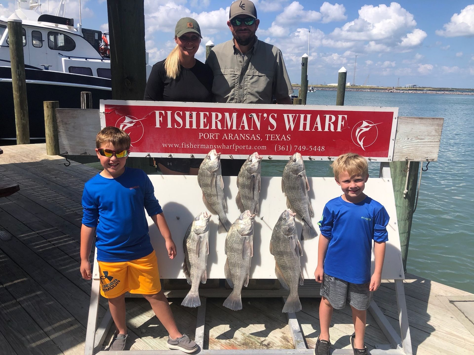 A family standing in front of a sign that says fisherman 's wharf
