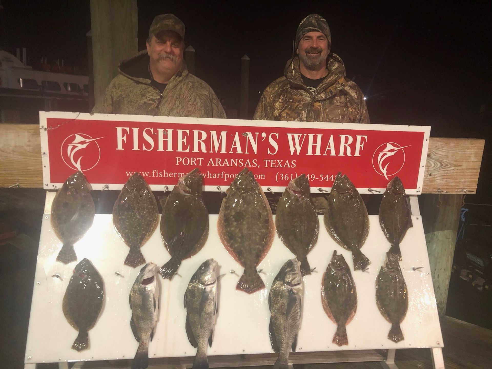 Two men standing next to a sign that says fisherman 's wharf