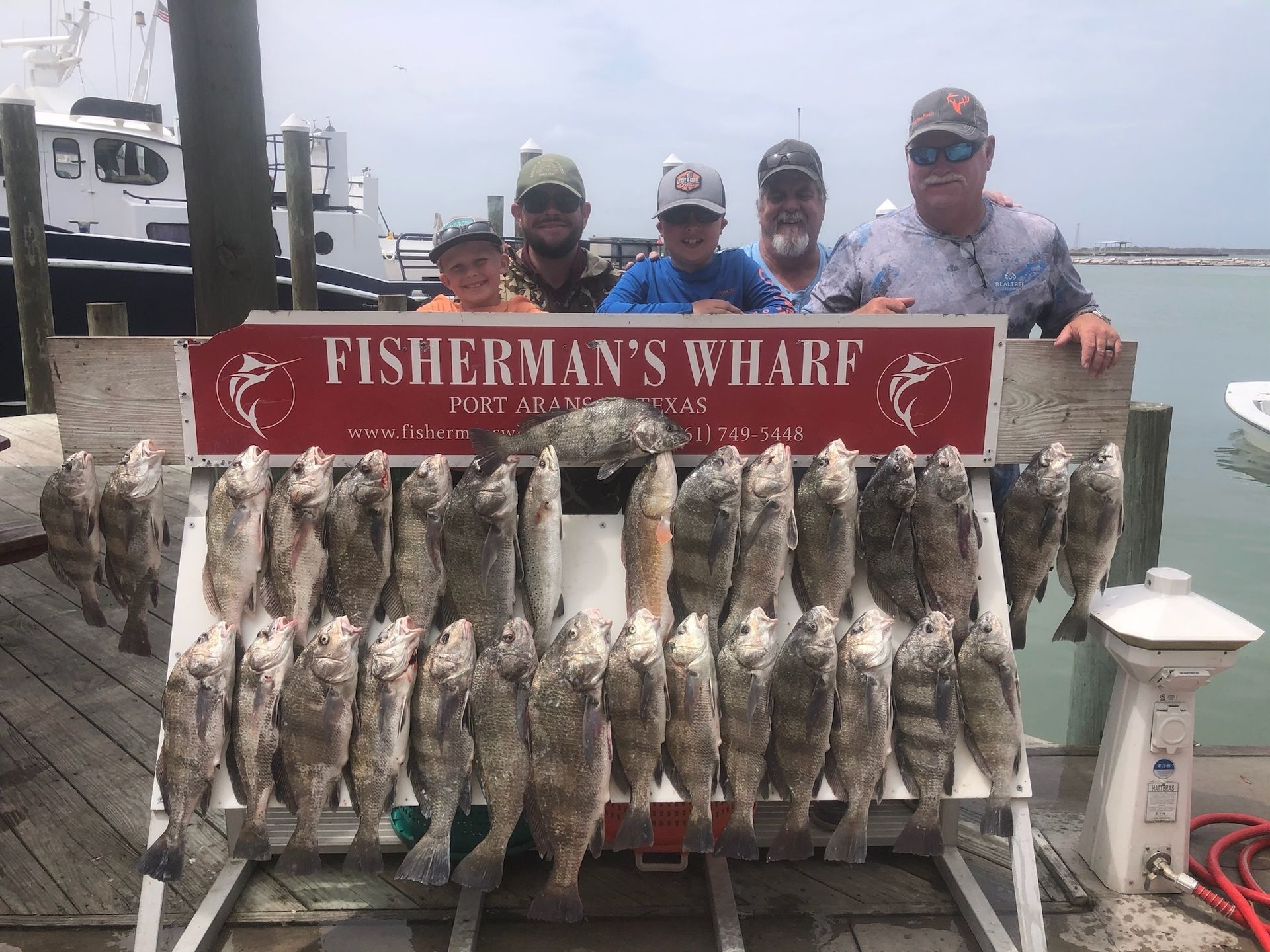 A group of men are standing in front of a sign that says fisherman 's wharf.