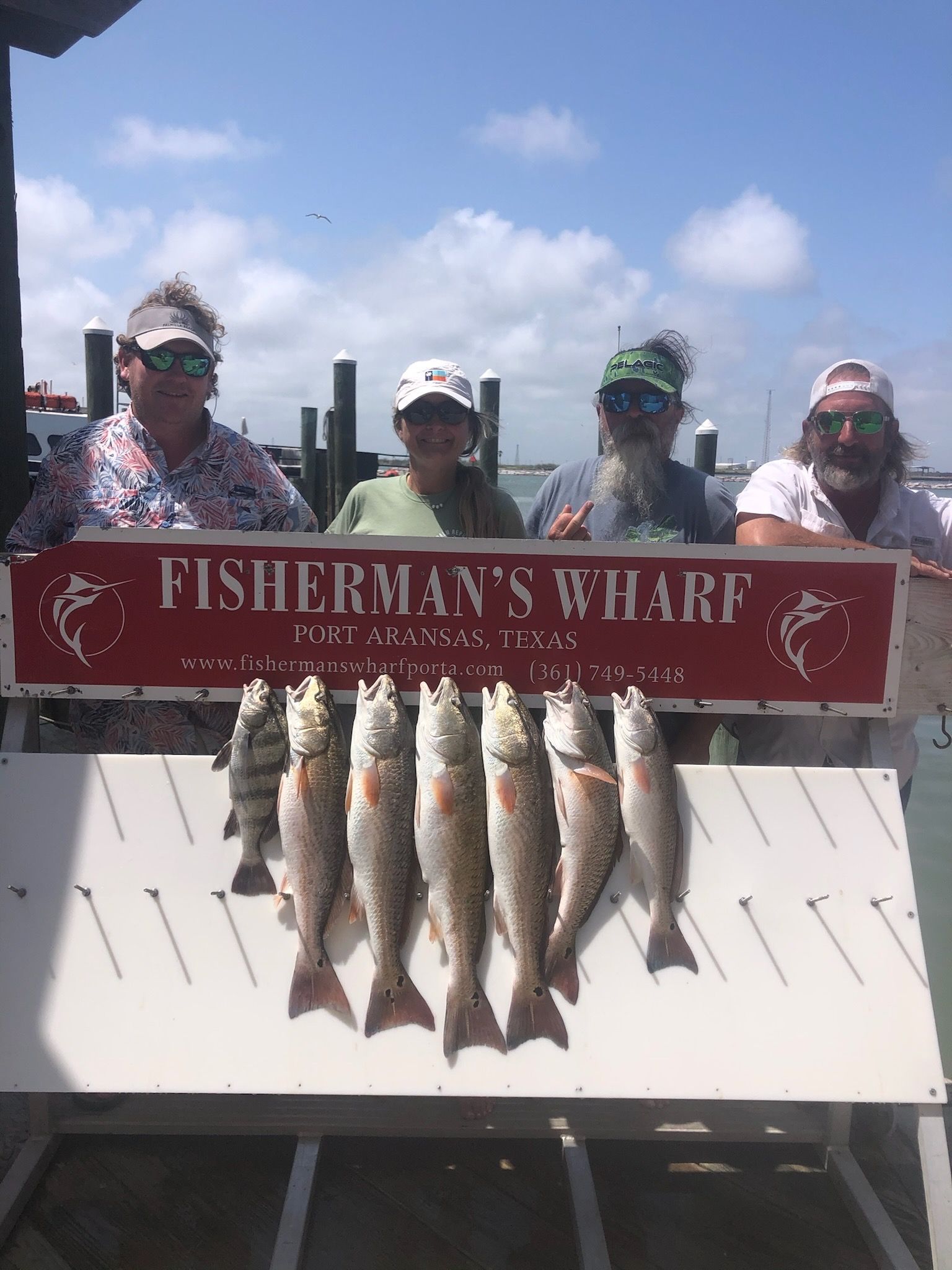 A group of people standing next to each other holding a sign that says fisherman 's wharf.