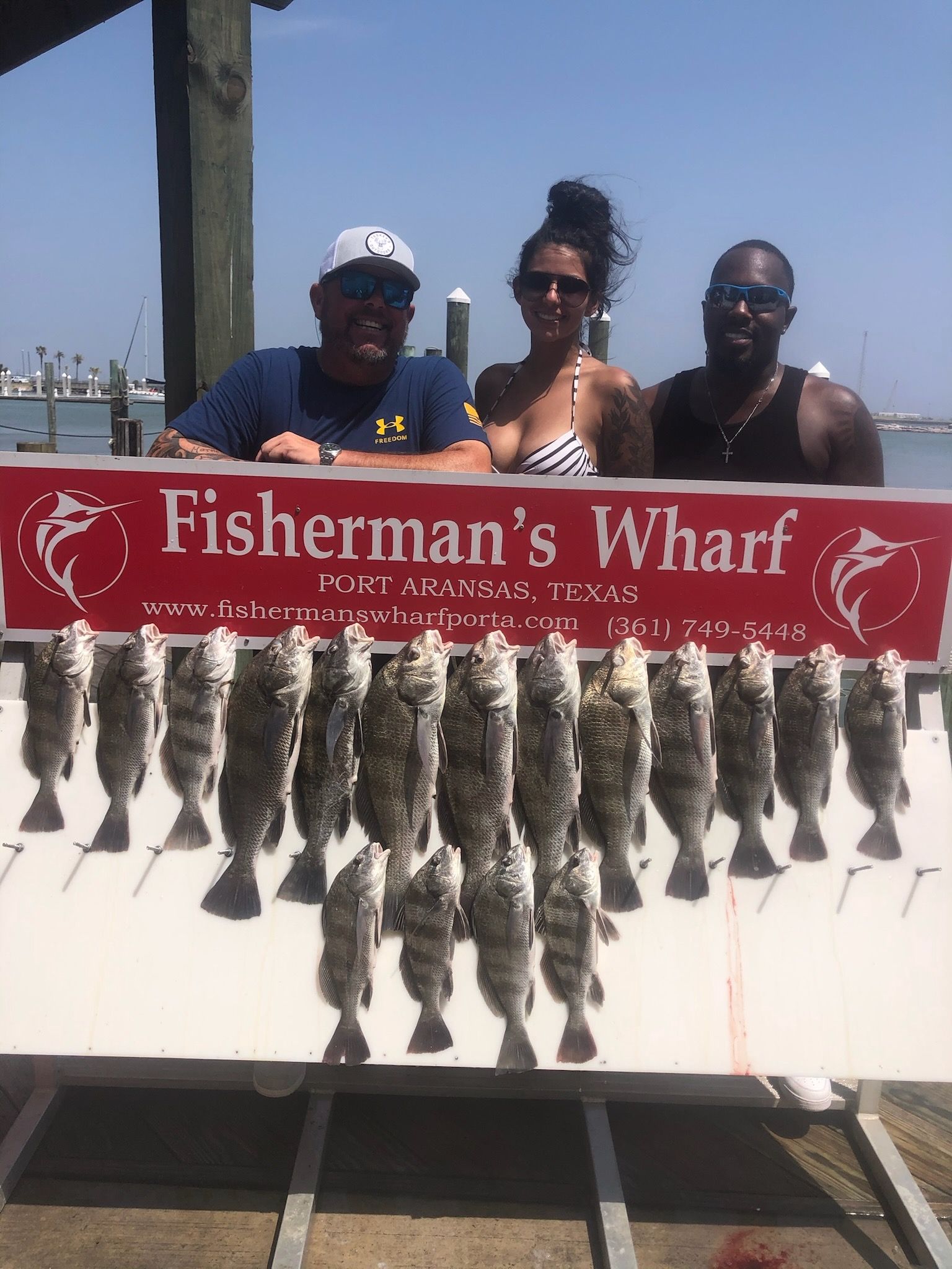 A group of people standing next to a sign that says fisherman 's wharf.