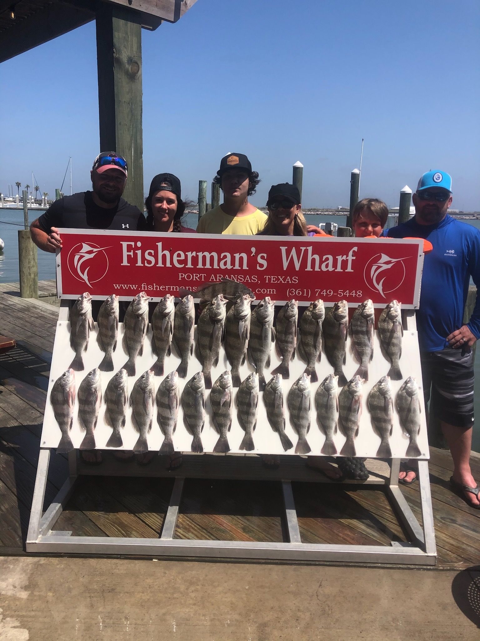 A group of people are standing around a sign that says fisherman 's wharf.