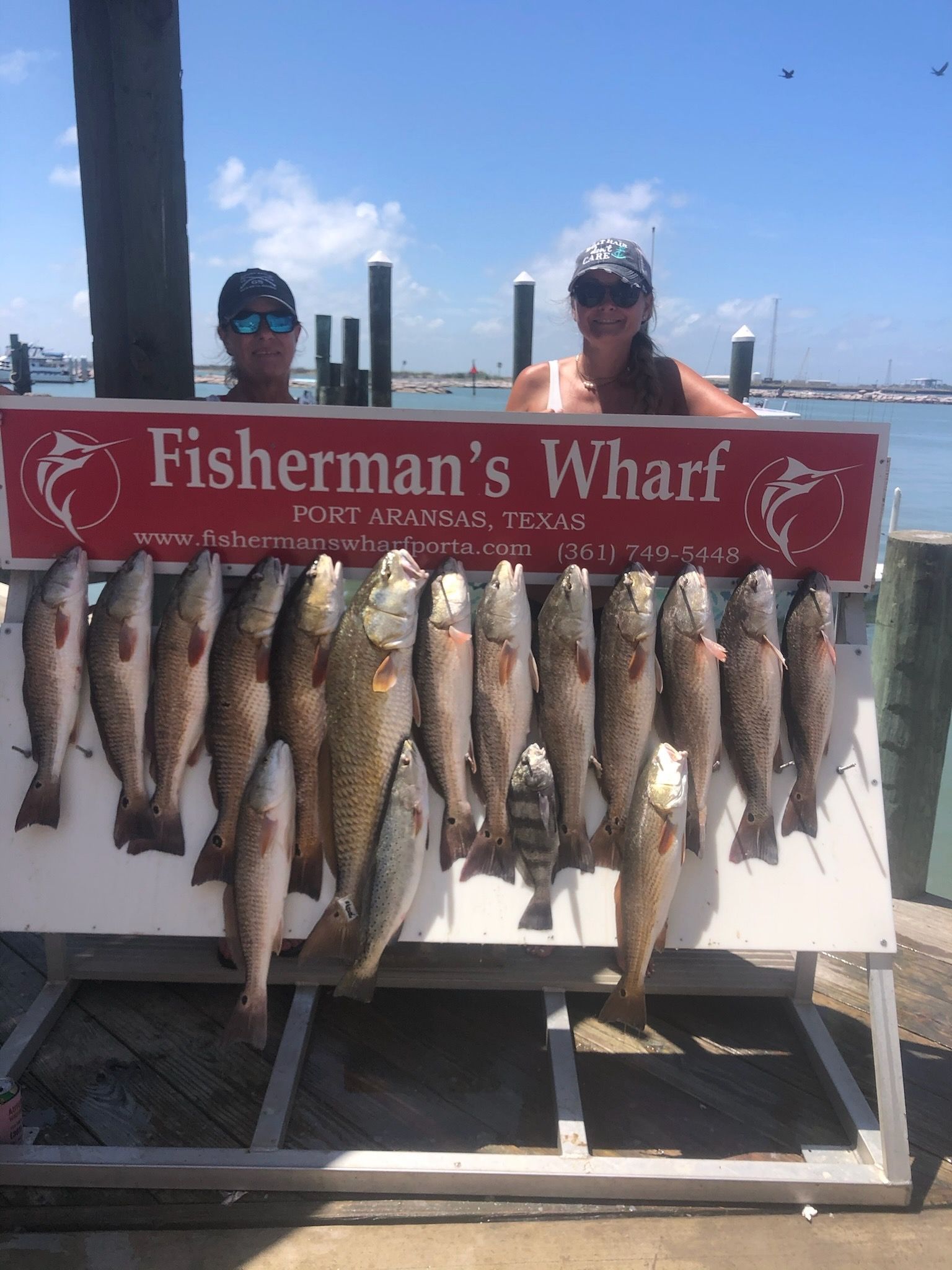 Two people holding a sign that says fisherman 's wharf