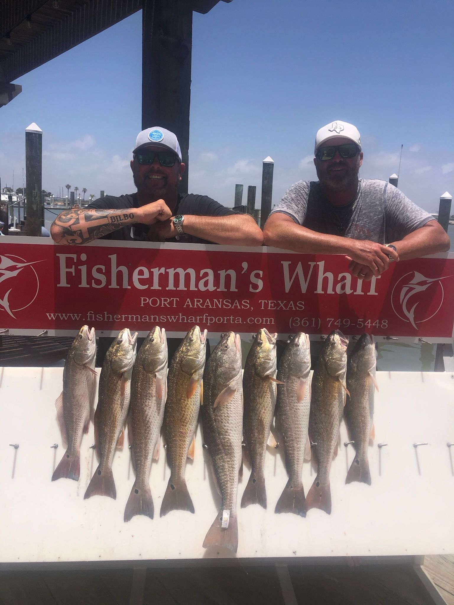 Two men are holding a sign that says fisherman 's wharf.