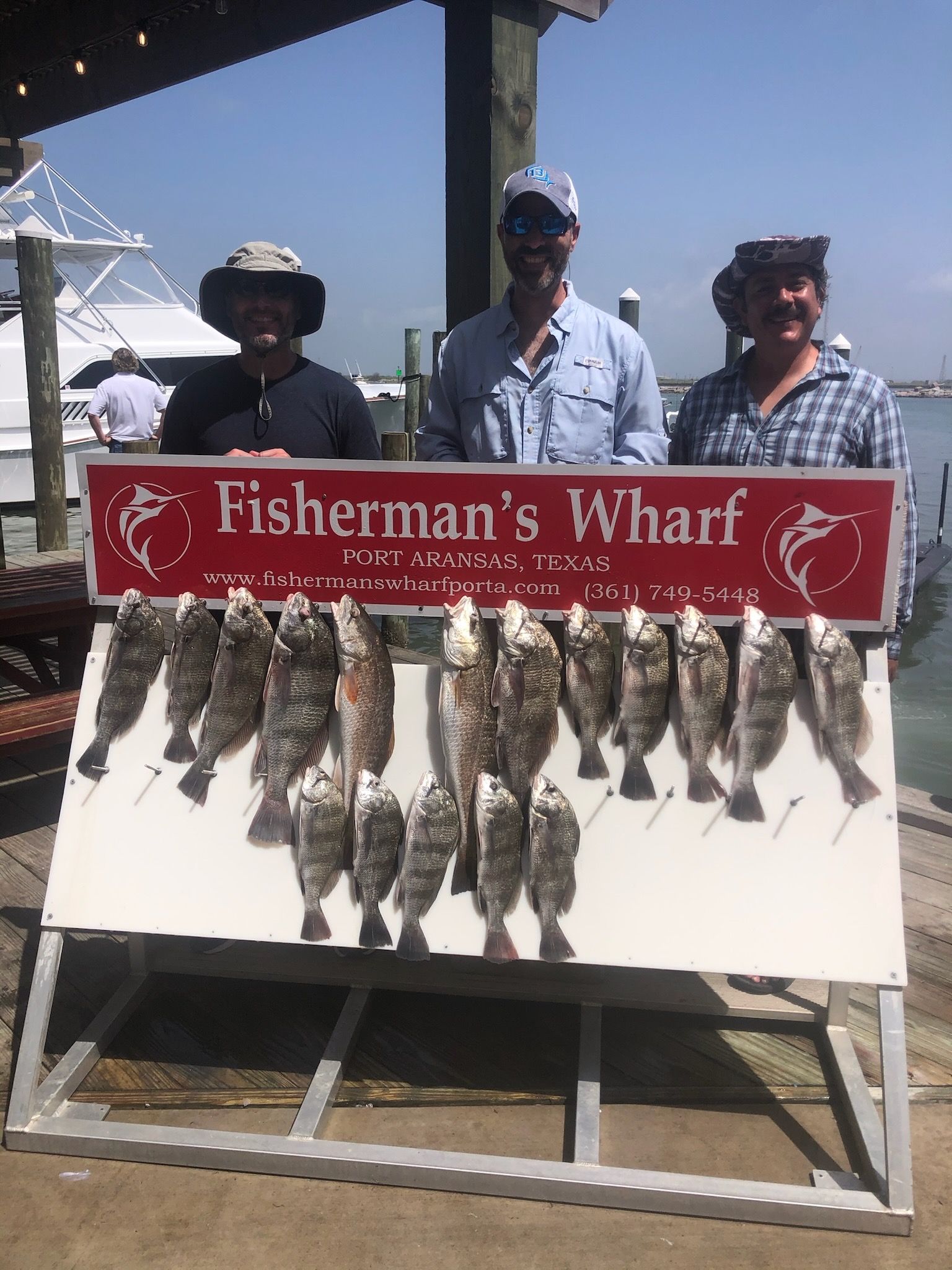 Three men are standing in front of a sign that says fisherman 's wharf