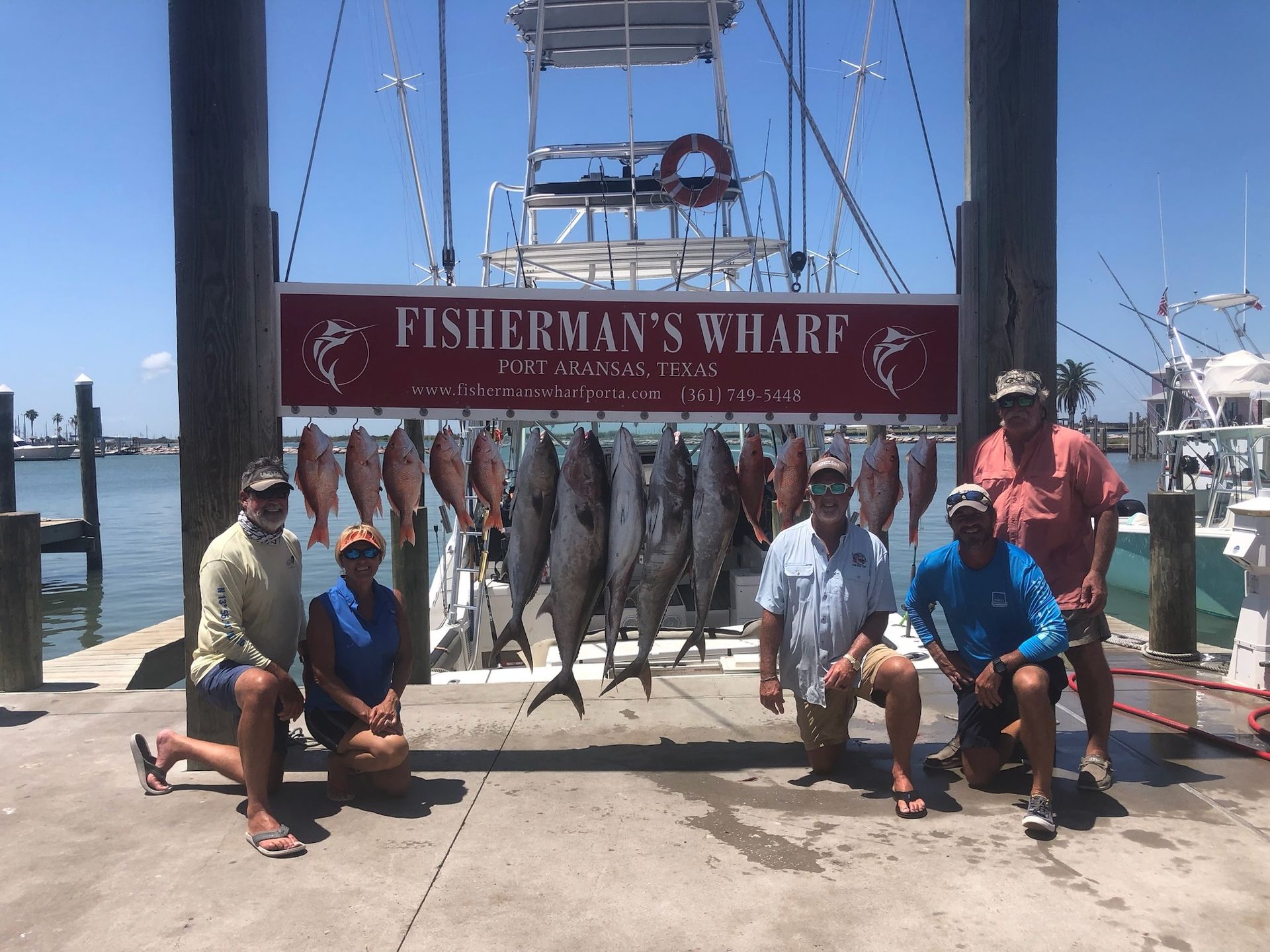 A group of men are posing for a picture in front of a sign that says fisherman 's wharf.
