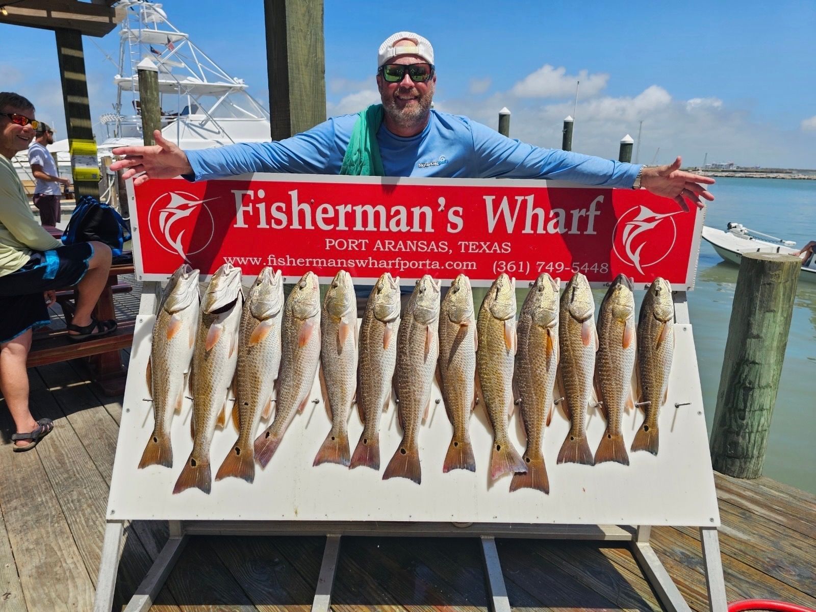 A man is standing in front of a sign that says fisherman 's wharf.