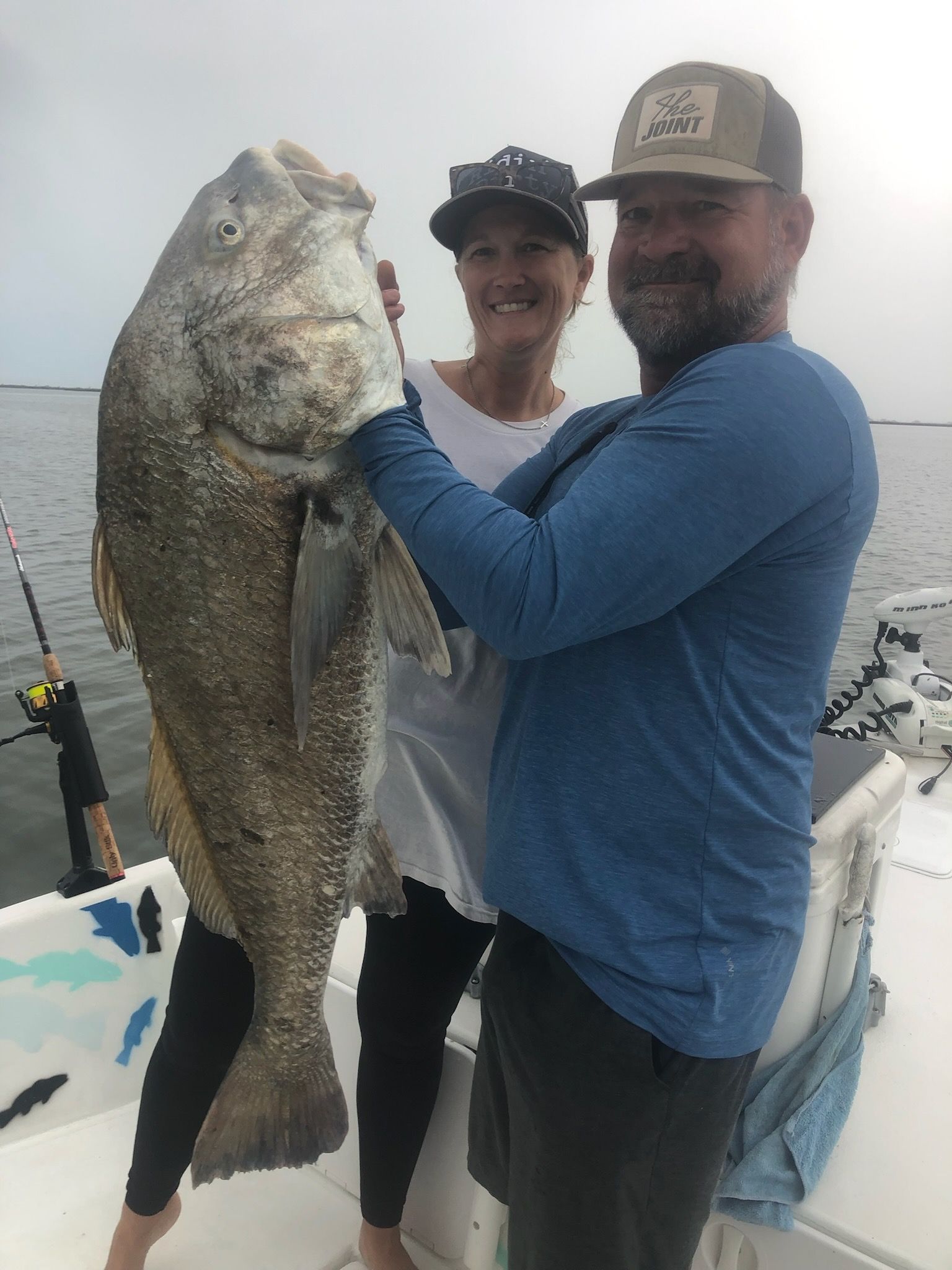 A man and a woman are holding a large fish on a boat.
