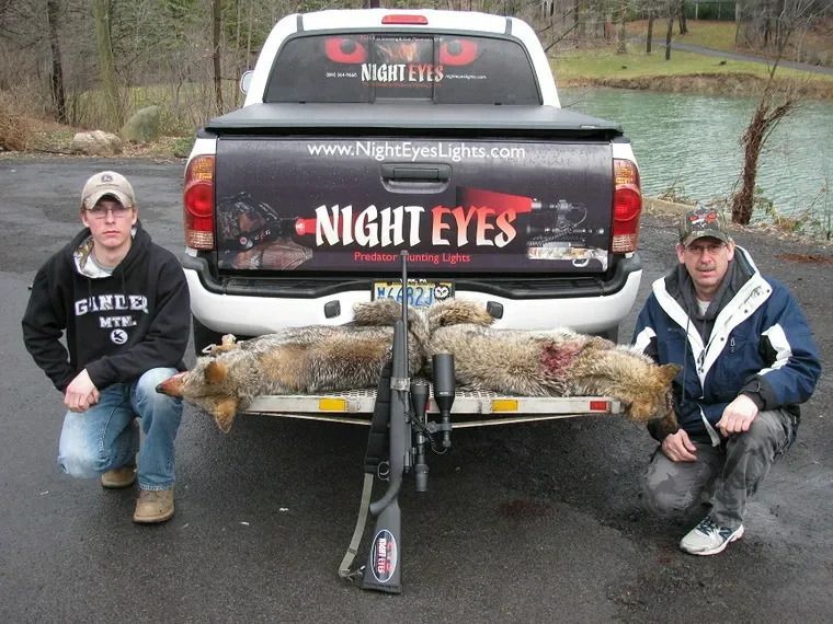 Two people posing beside a pickup truck with large fish on a trailer by a river