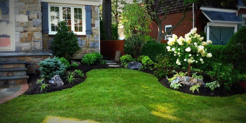 A lush green lawn in front of a stone house