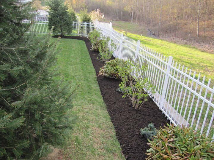 A white fence surrounds a lush green yard