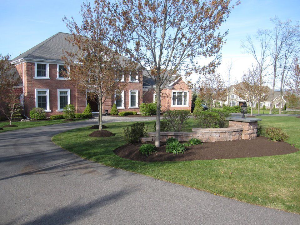 A large brick house sits in the middle of a lush green neighborhood