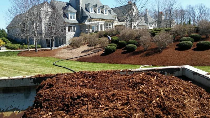 A pile of mulch is sitting in front of a large house
