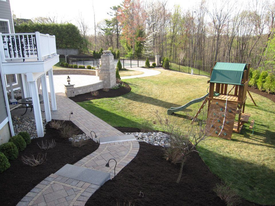 A large backyard with a playground and a walkway