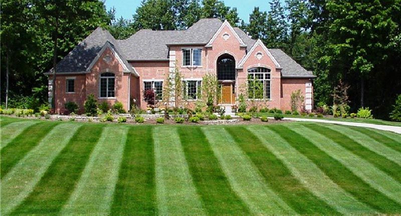 A large brick house with a lush green lawn in front of it